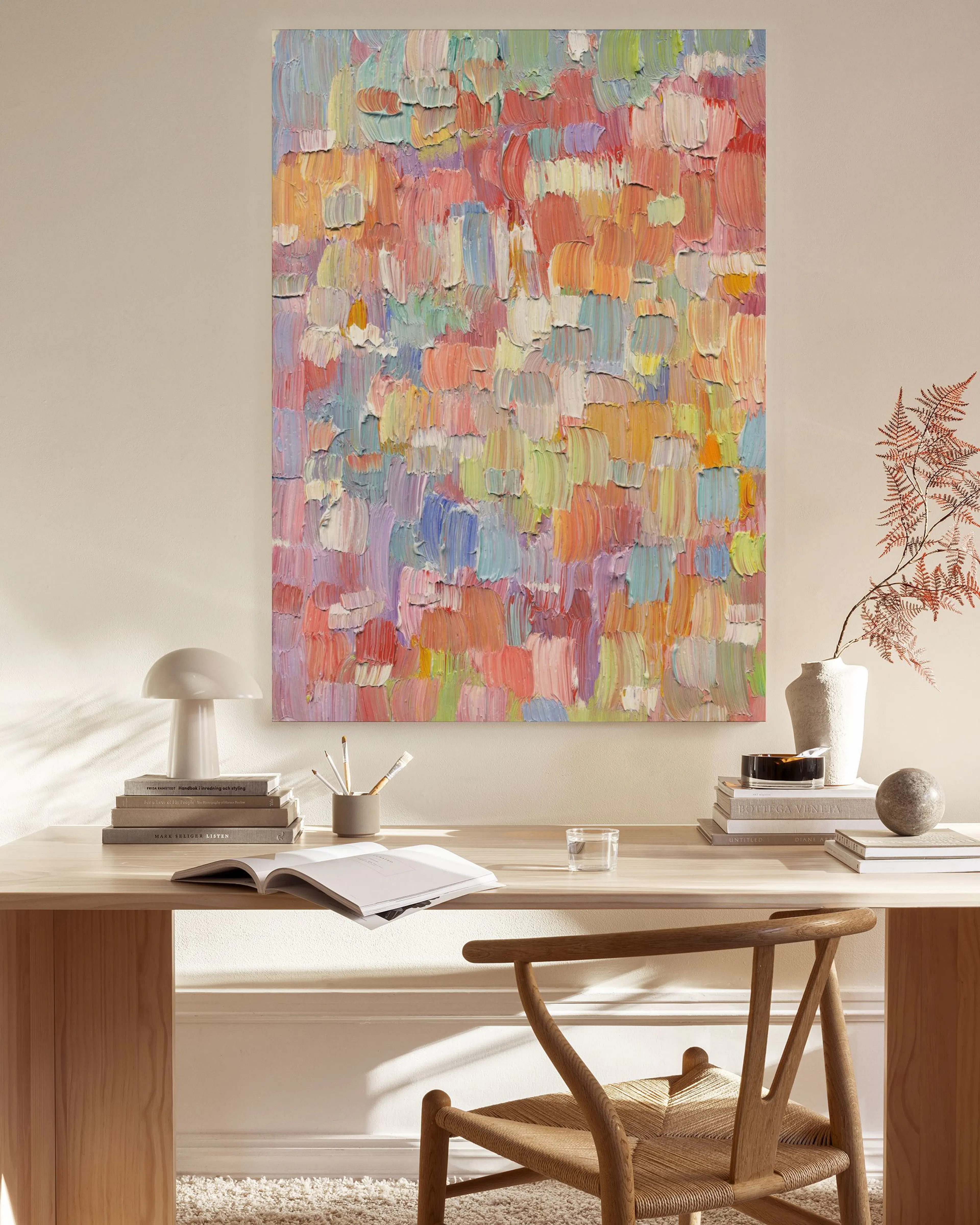Textured abstract canvas print with colorful brushstrokes in pink, orange, blue, and green, displayed in a light living room.