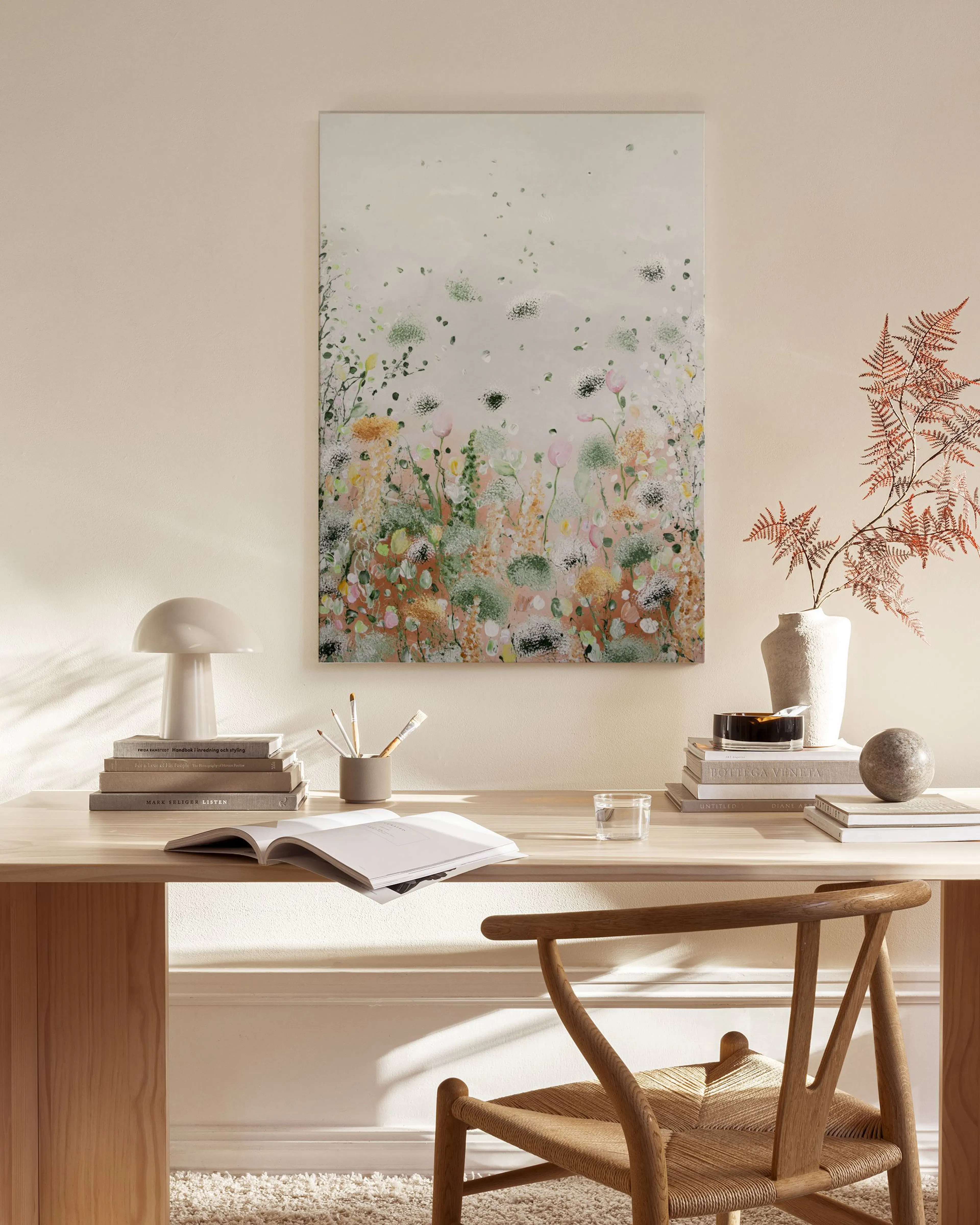 Leinwandbild mit pastellfarbenen Blumen und Gräsern, hängt über einem Holzregal im Wohnzimmer.