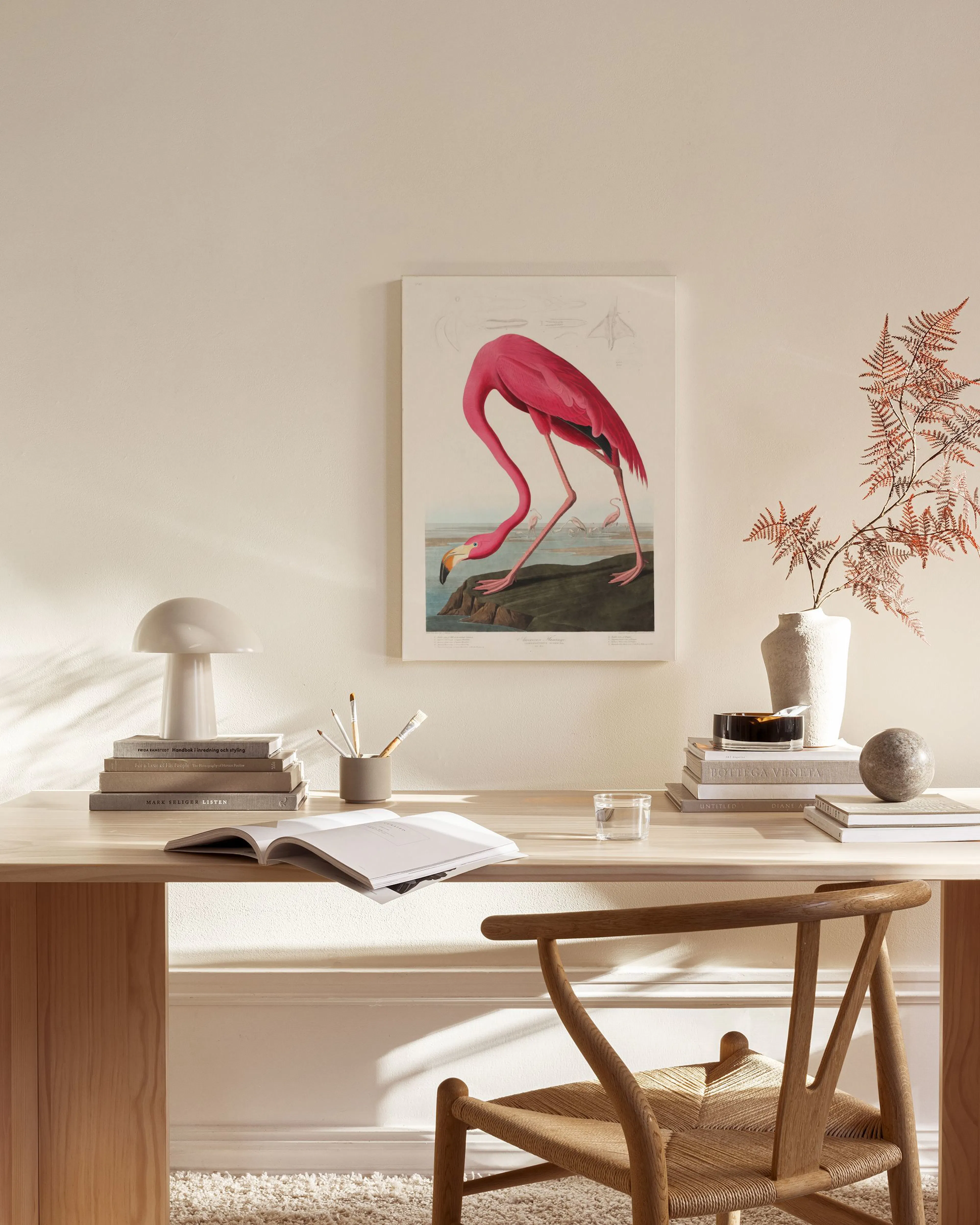 Kanvaasi esittää vaaleanpunaisen flamingon juomassa vedestä, ripustettuna moderniin olohuoneeseen.