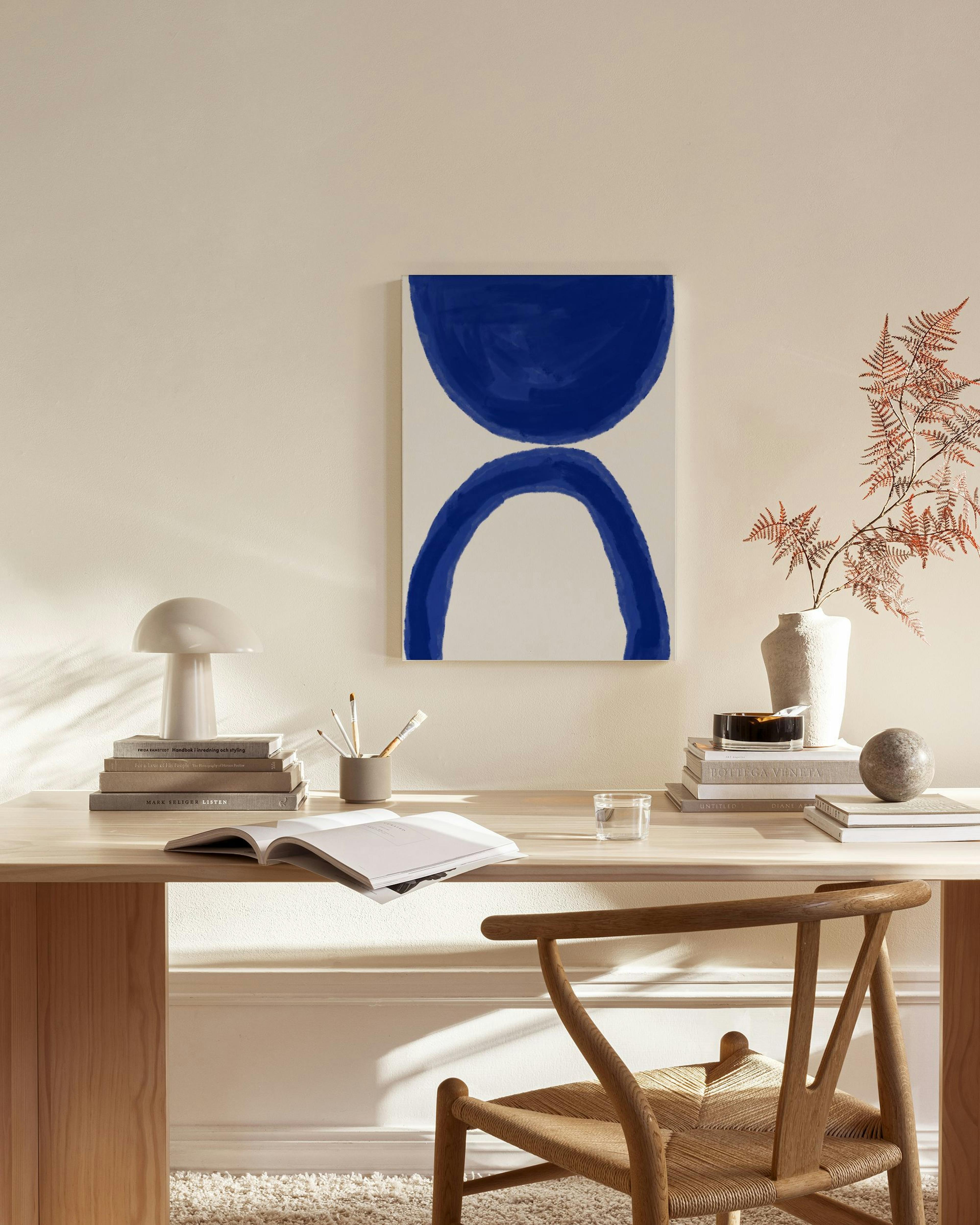 Stampa su tela astratta con forme blu brillante su sfondo bianco, appesa in un soggiorno moderno.