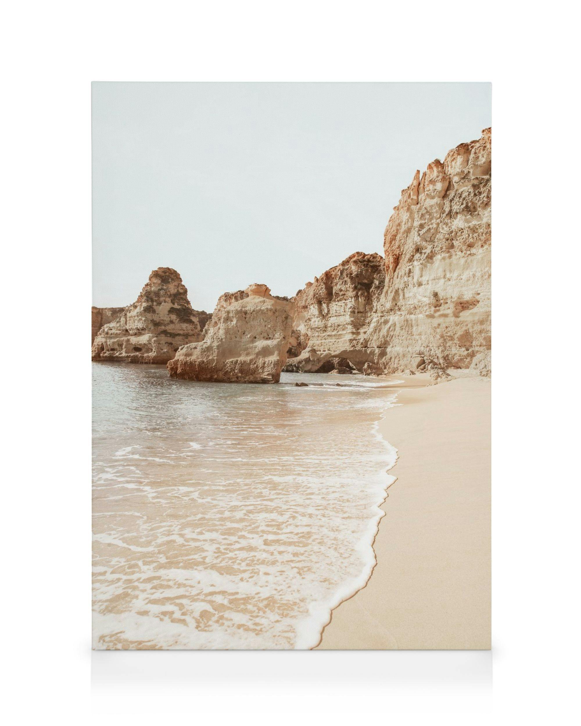 Pláž Algarve v béžových barvách, klidné pobřeží s útesy a pískem, vlny jemně omývající břeh