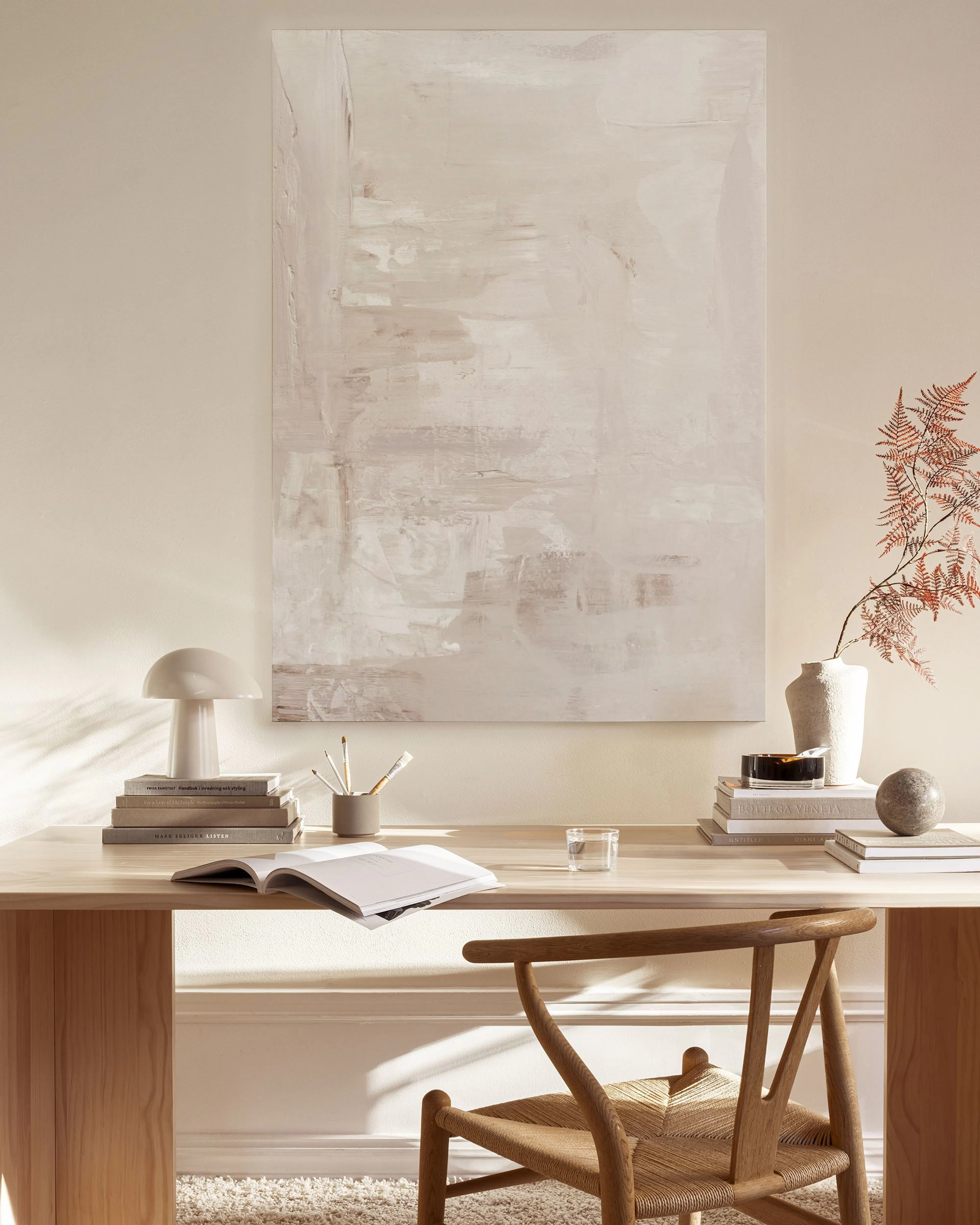 Abstract canvas print in muted beige and grey tones with textured brushstrokes, hanging in a modern living room above a wooden c