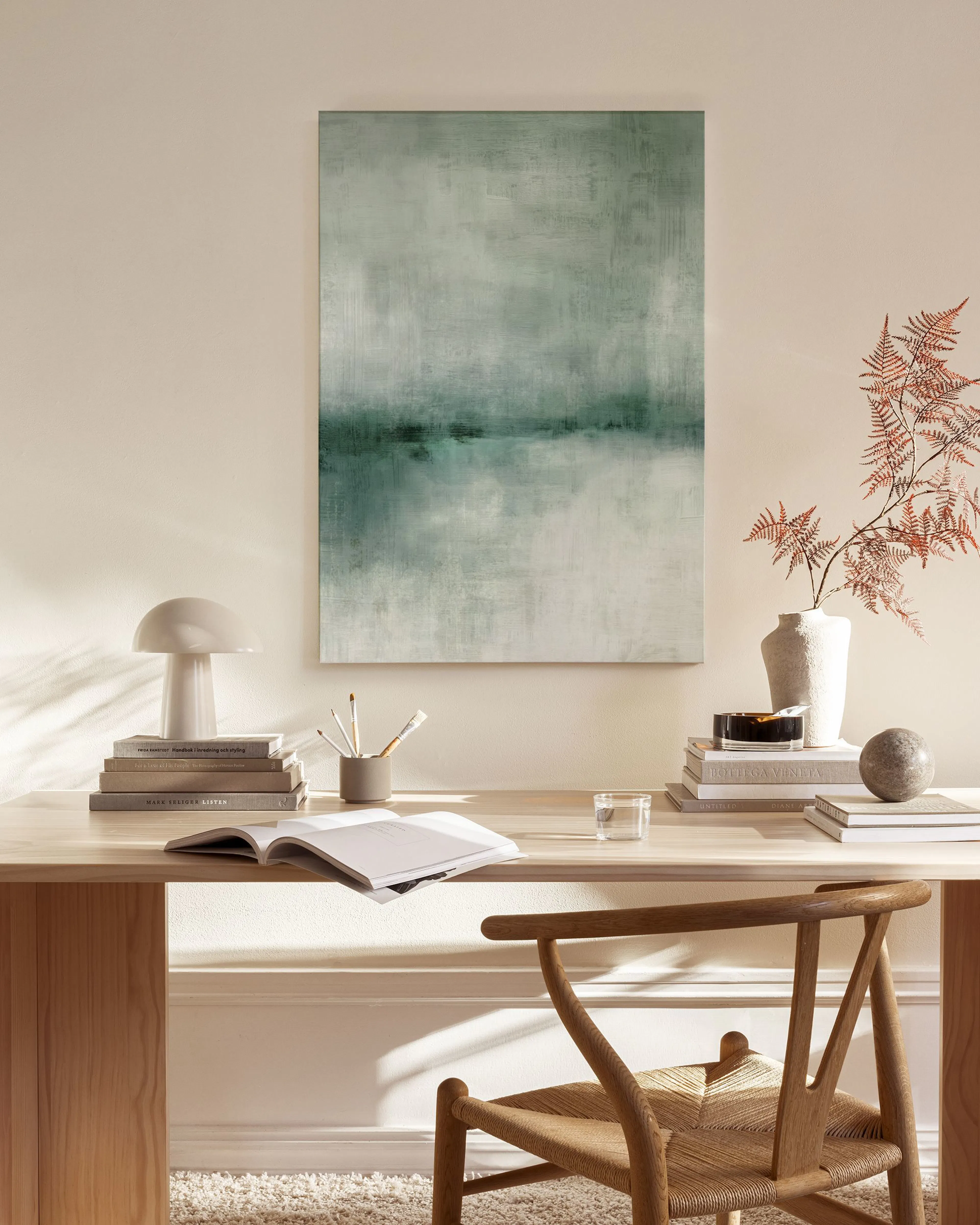 Grün-graues Leinwandbild mit abstrakten Horizontlinien über einer Holzkommode in einem hellen Wohnzimmer.