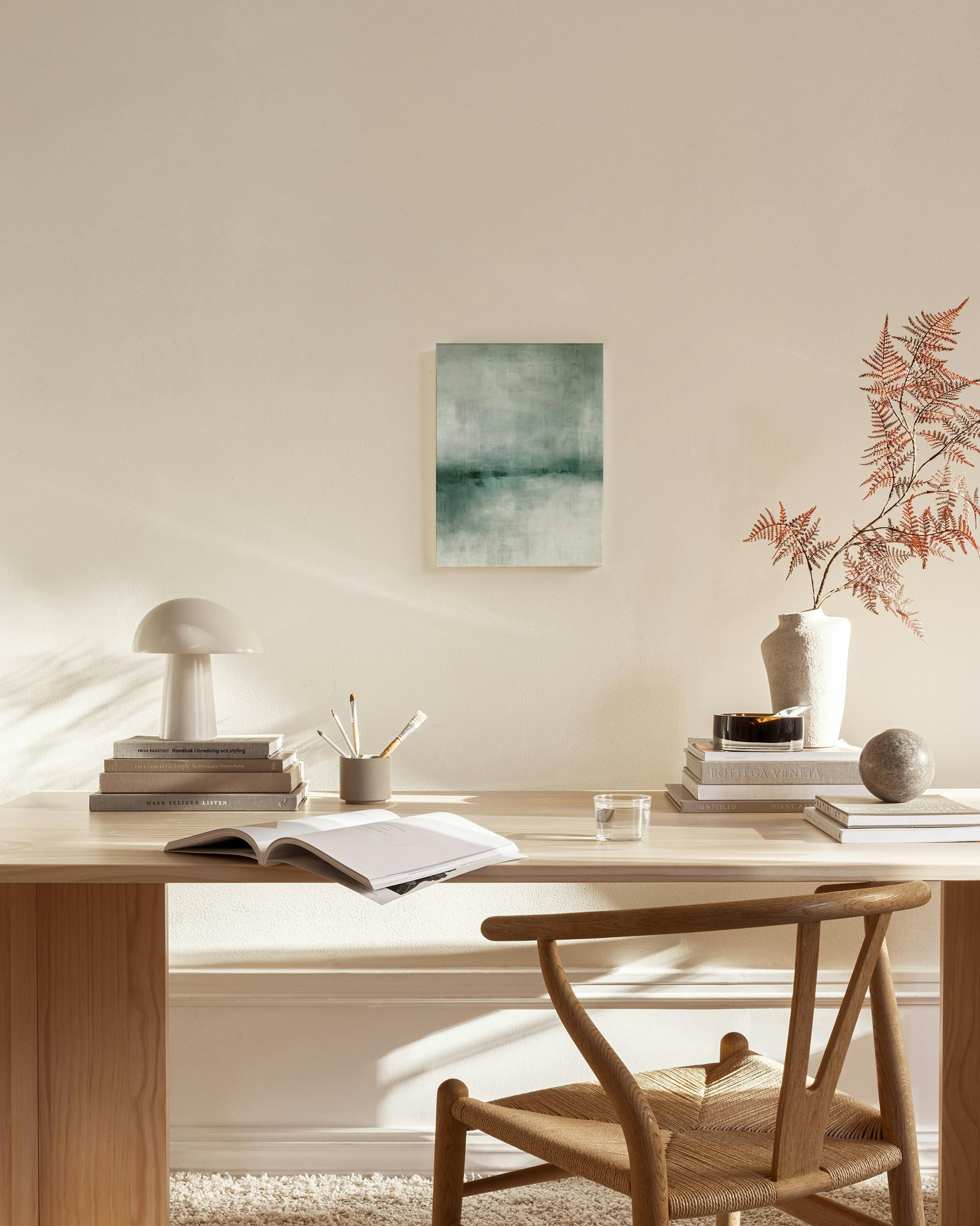 Tela decorativa de paisagem abstrata em tons de verde e cinzento, com pinceladas que sugerem água, pendurada numa sala de estar 