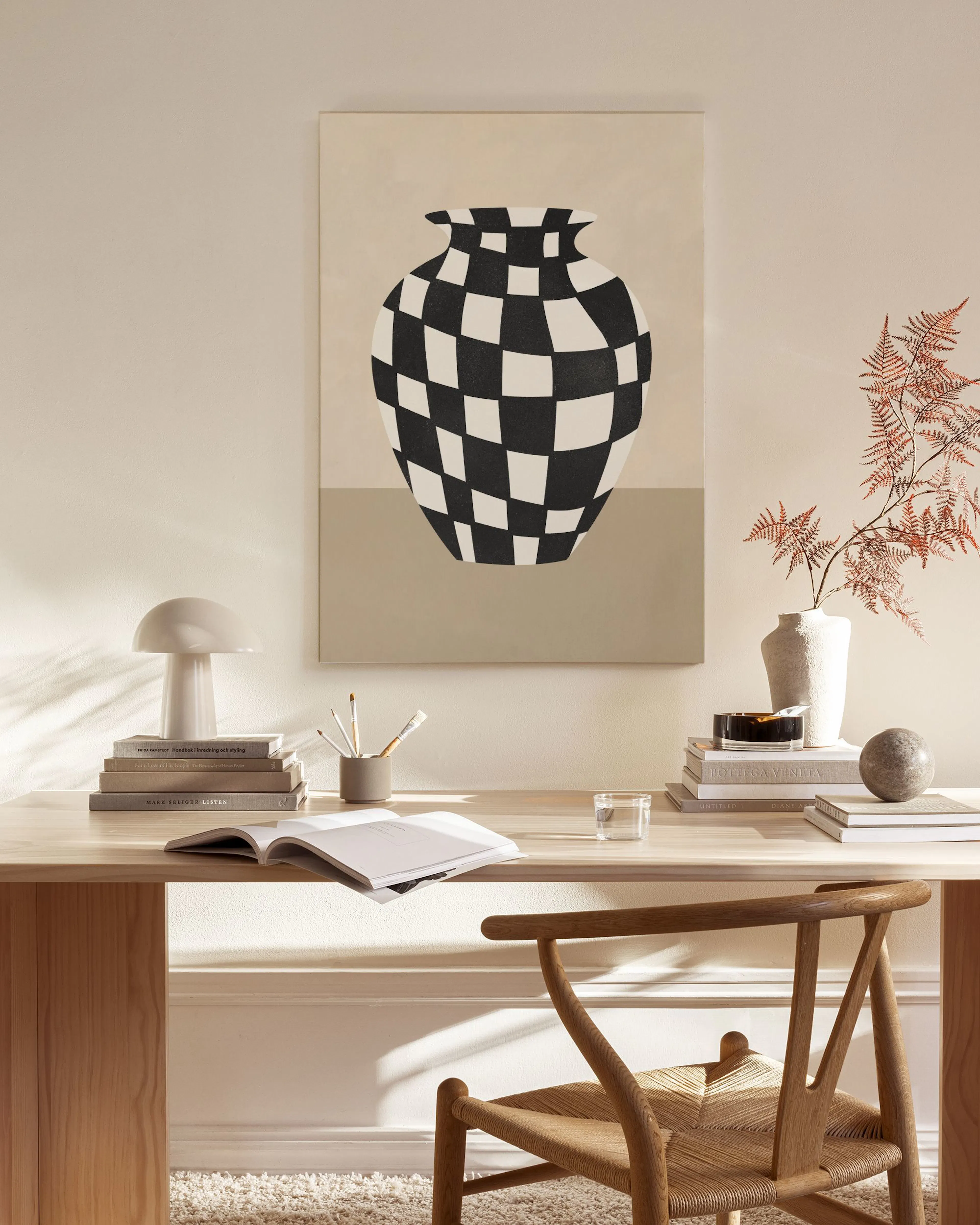 Lienzo de un jarrón blanco y negro a cuadros, colgado en una sala de estar moderna con muebles de madera clara.