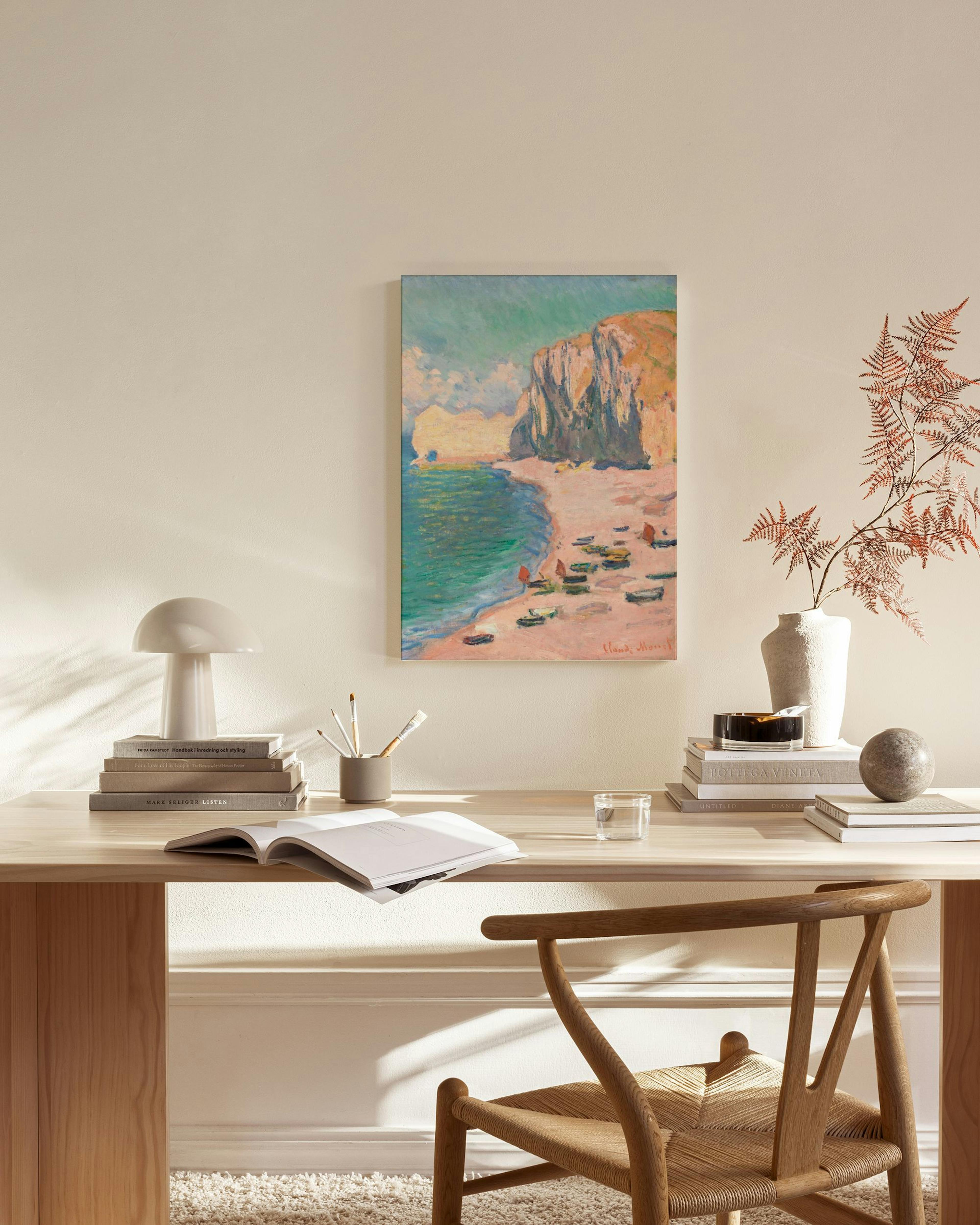 Obraz na plátně s pobřežní krajinou, loděmi na pláži a útesy v obývacím pokoji s křeslem.