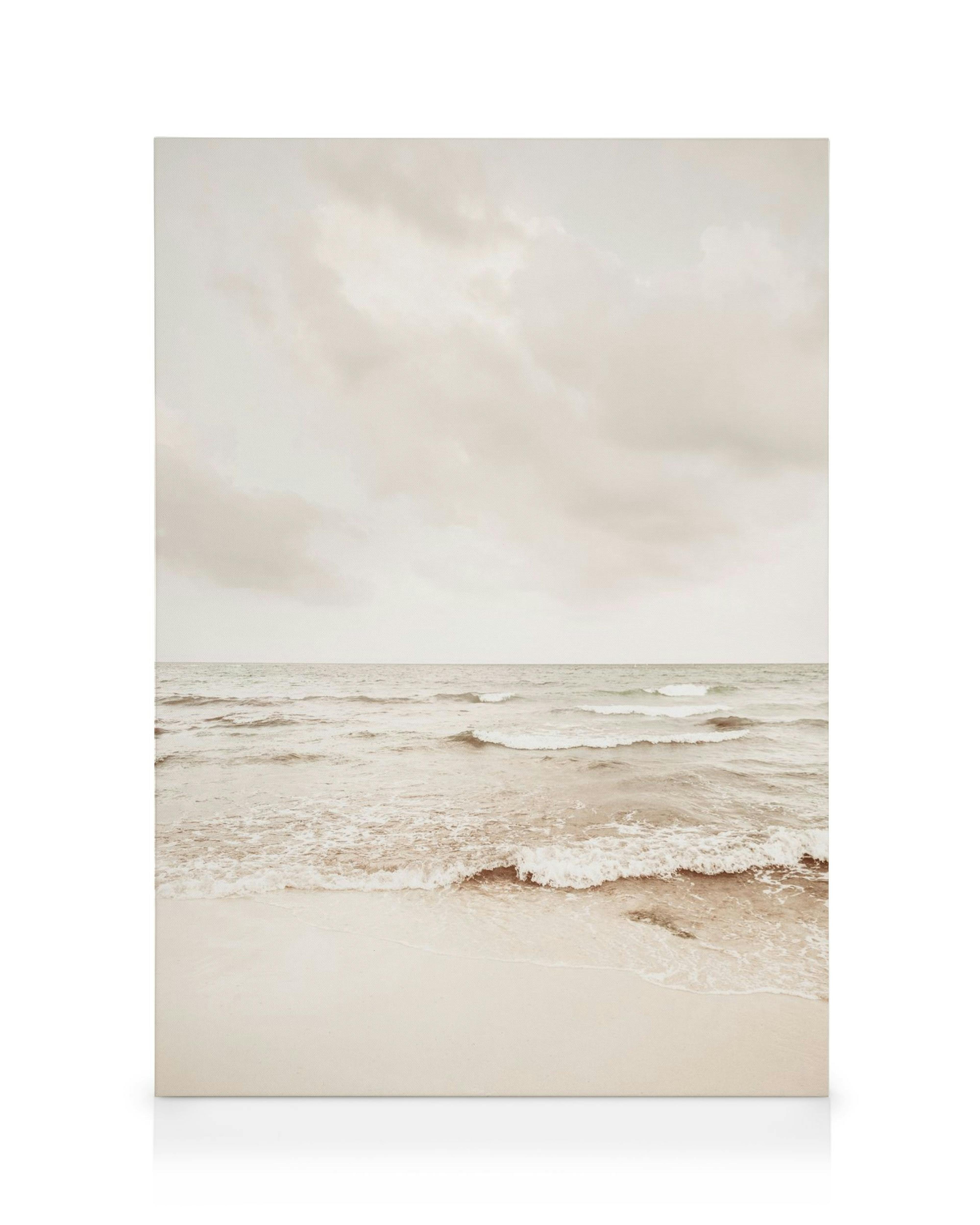 Rantakanvaasi pilvisenä päivänä, tyyni meri ja aallot beigen sävyissä