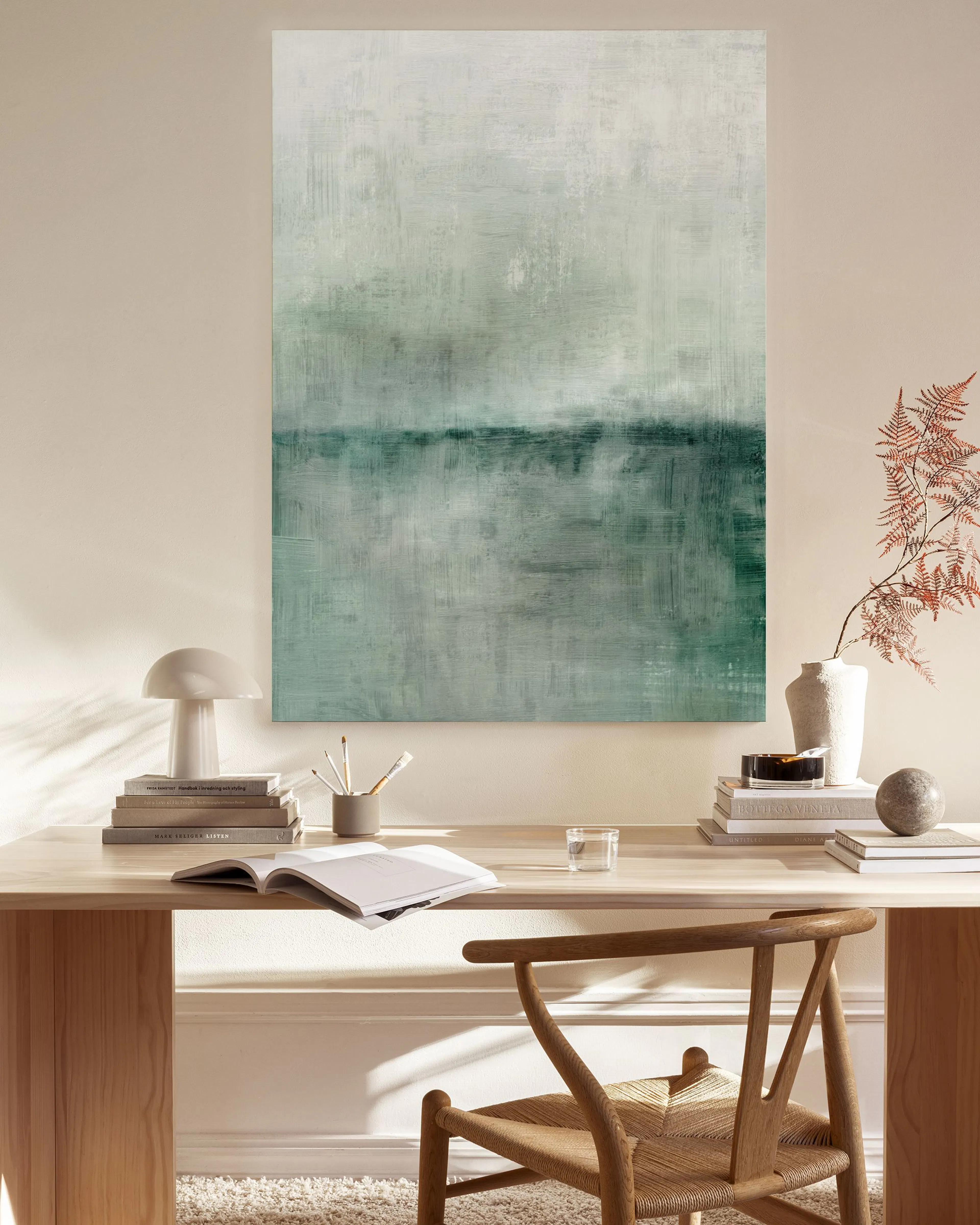 Lienzo abstracto en tonos verde agua y blanco, colgado sobre un mueble bajo de madera en una sala moderna.