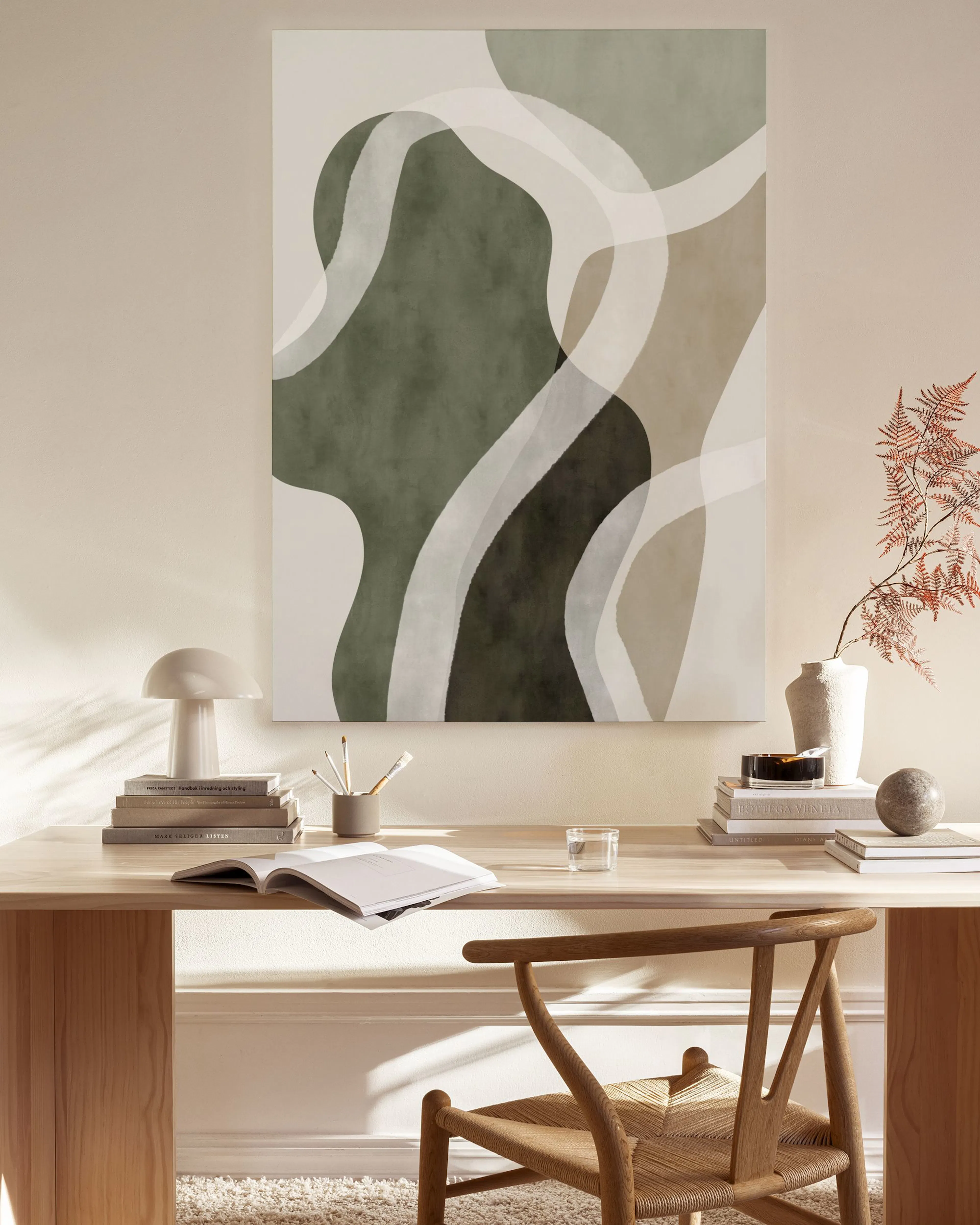 Leinwandbild mit organischen Formen in Grün, Beige und Dunkelbraun, darüber weiße, fließende Linien. Hängt in einem hellen Wohnz