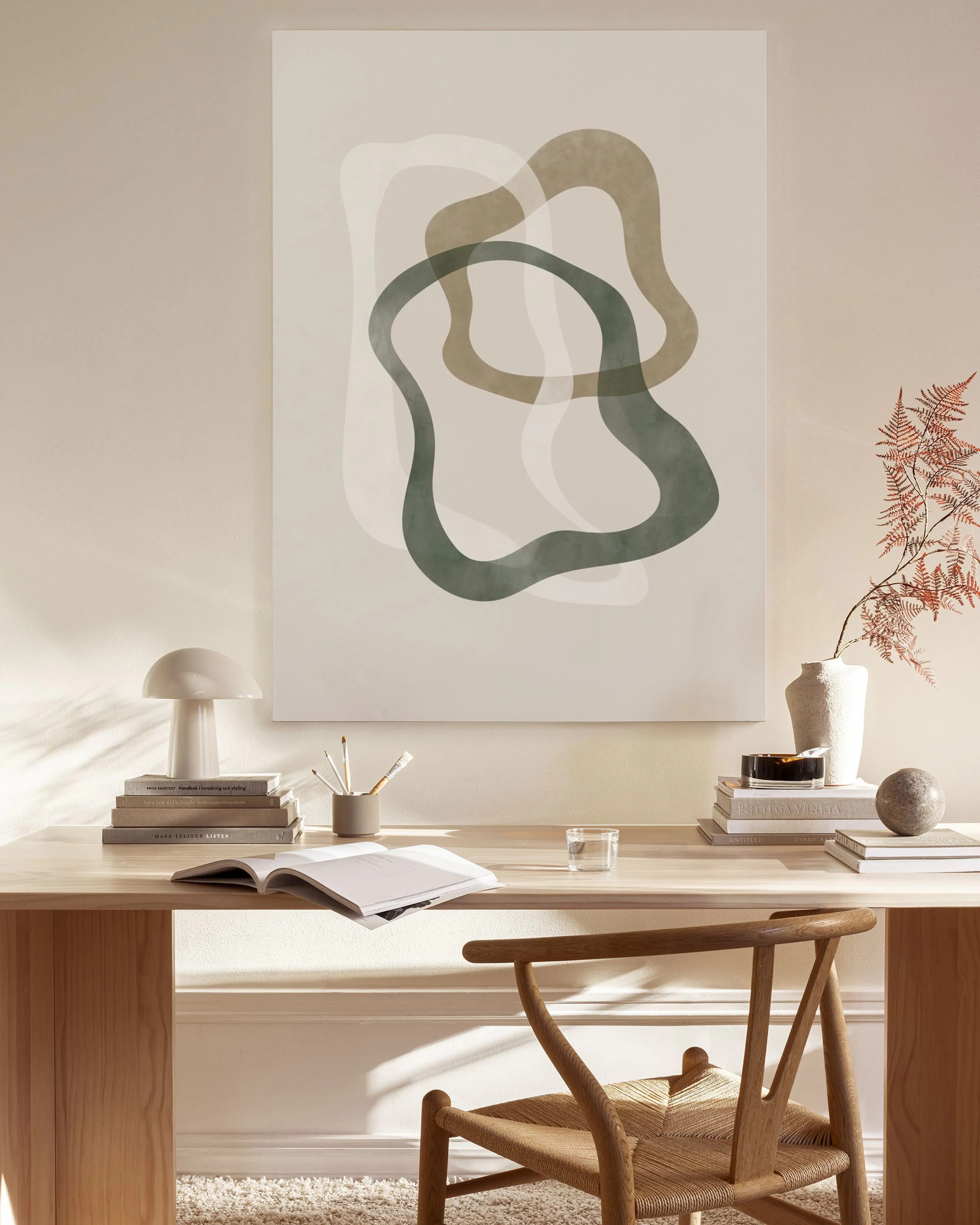 Canvas met organische vormen in groen en beige, hangend in een minimalistische woonkamer boven een houten dressoir.