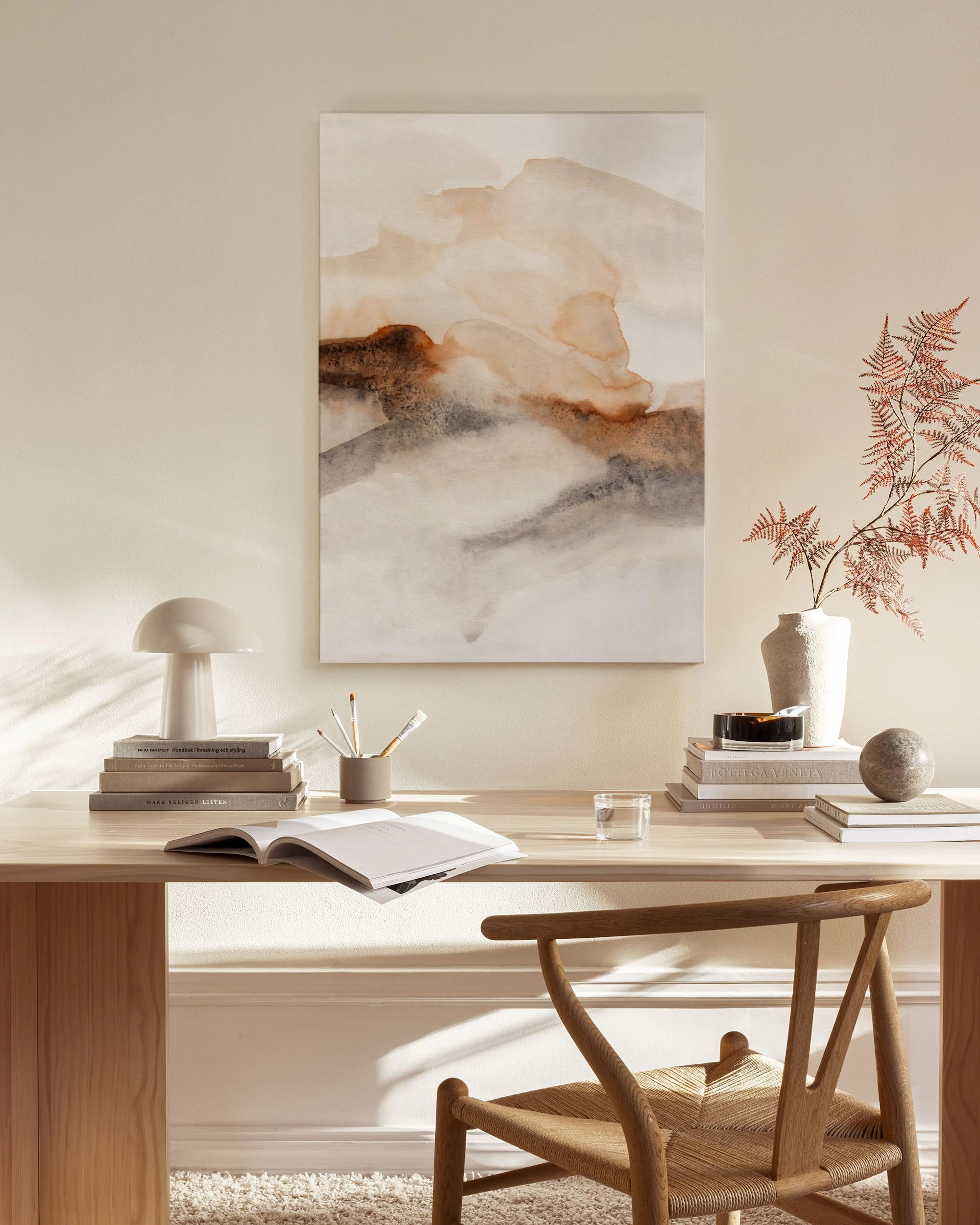 Canvas met abstracte vormen in bruin, beige en grijs, hangend boven een houten dressoir in een woonkamer.