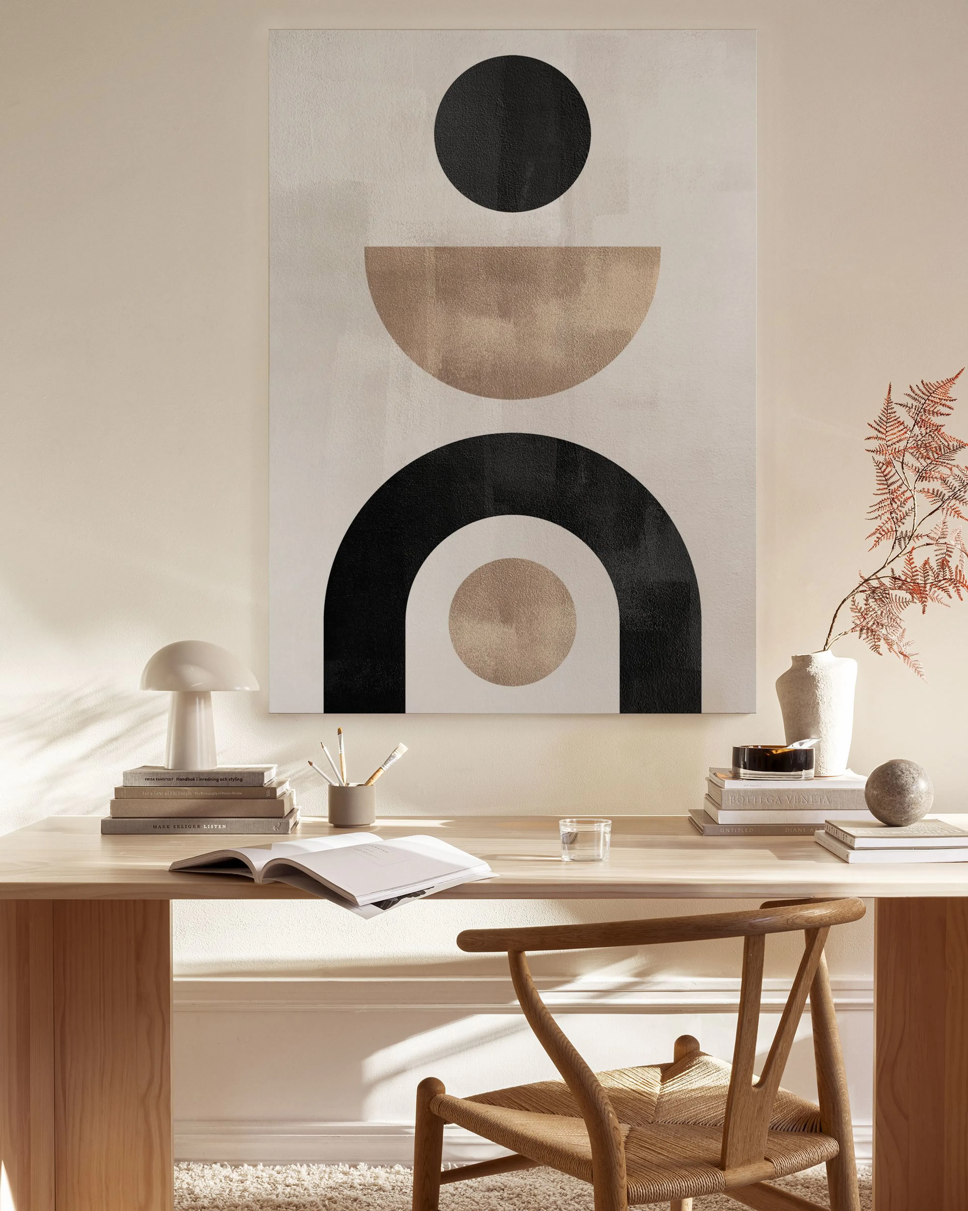 Abstract canvas print with black, beige, and white geometric shapes, hanging in a minimalist living room.