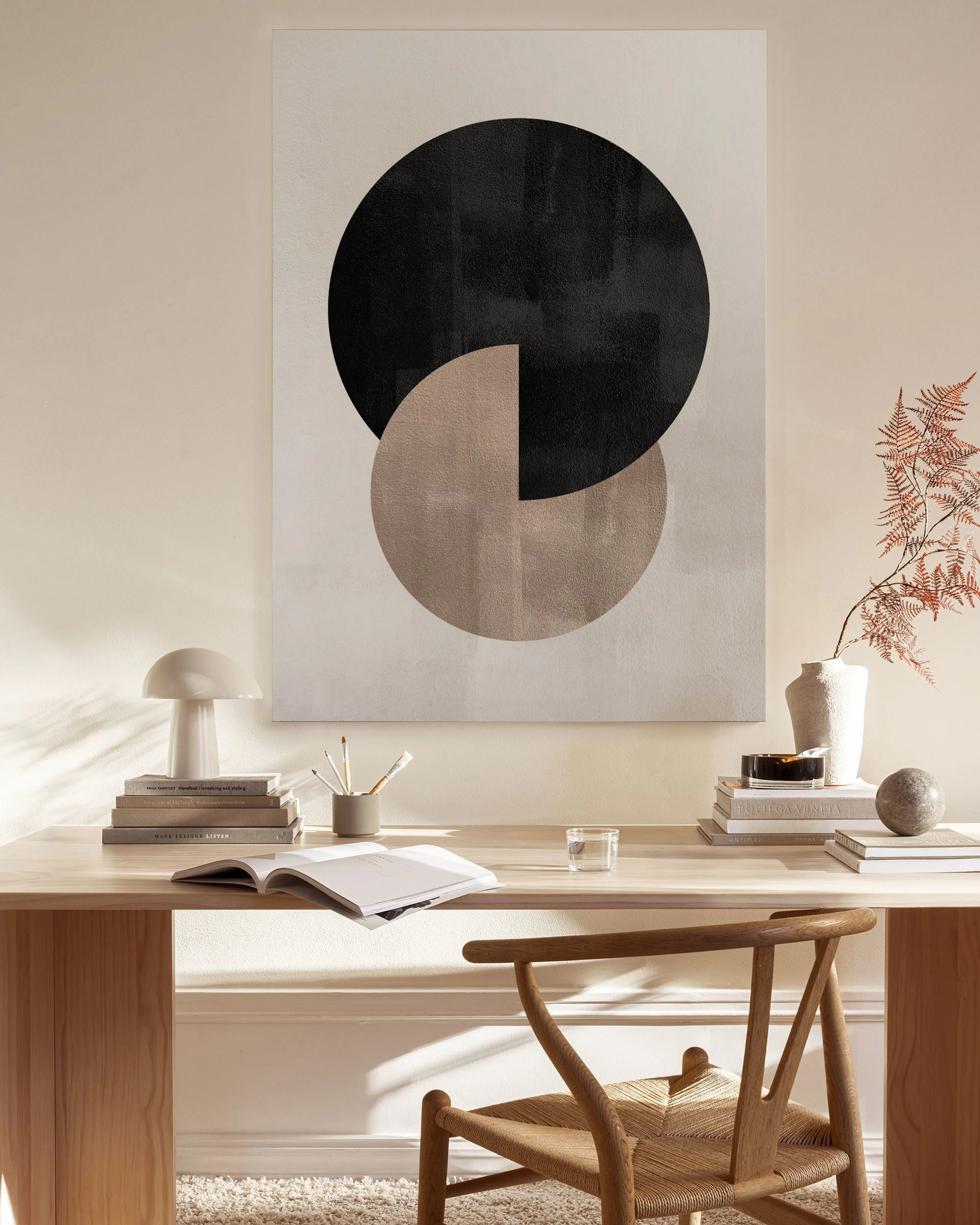 Canvas met zwarte en bruine geometrische cirkels, hangend boven een houten dressoir in een lichte woonkamer.