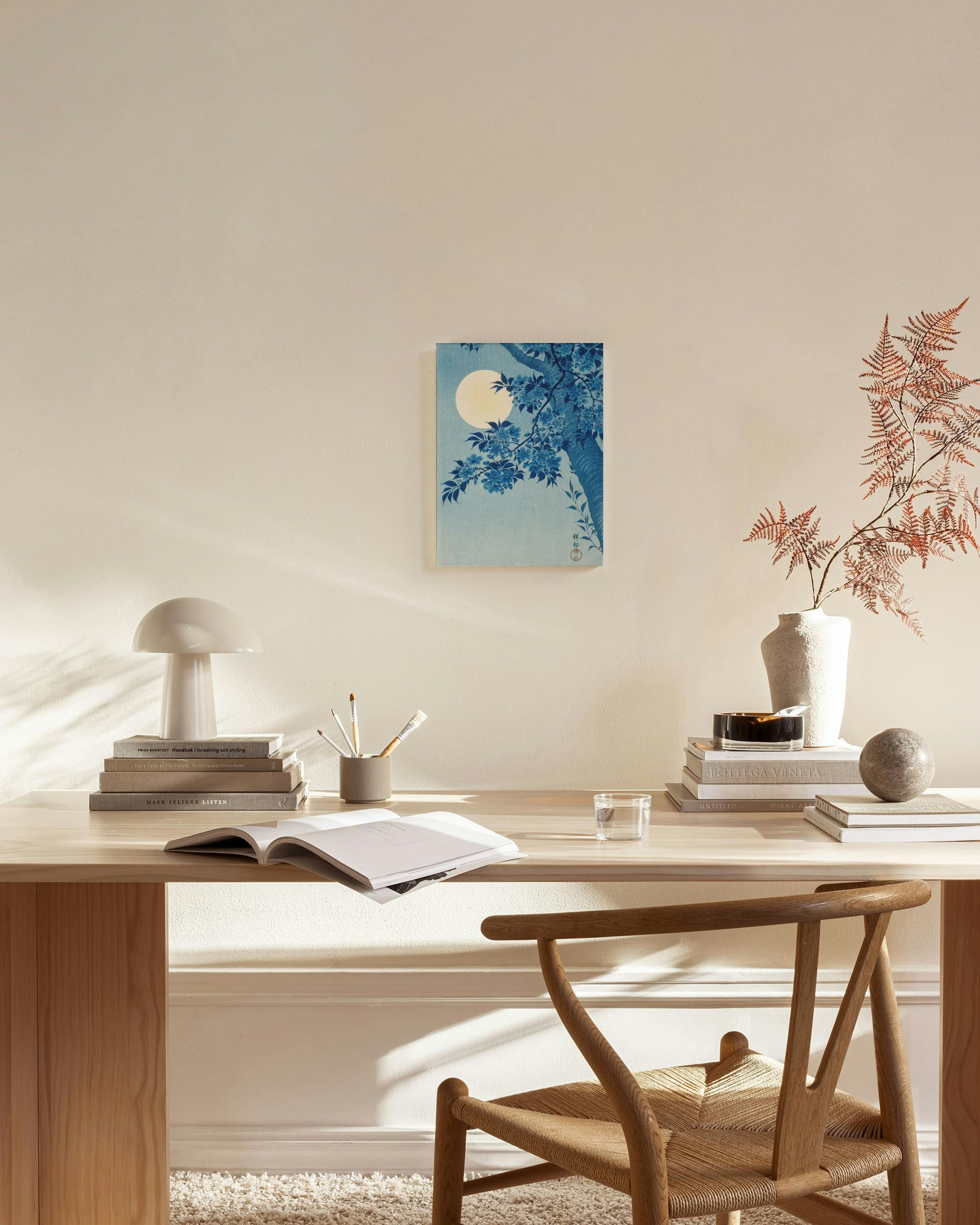 Stampa su tela giapponese blu di un albero in fiore e luna, appesa sopra una panca in un soggiorno moderno.