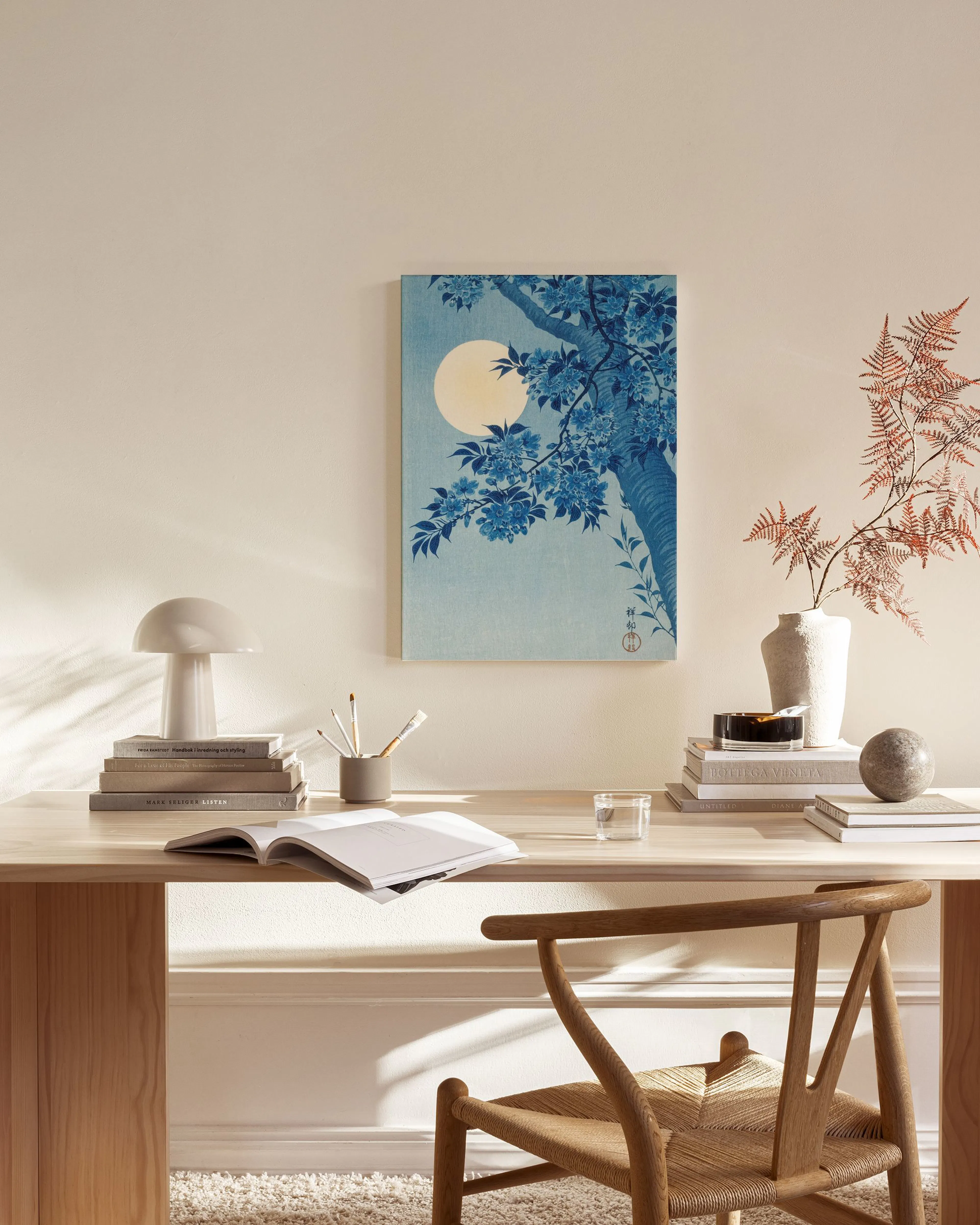Leinwandbild mit blauem Baum und Mond im japanischen Stil, hängend in einem hellen Wohnzimmer über einem Sideboard.
