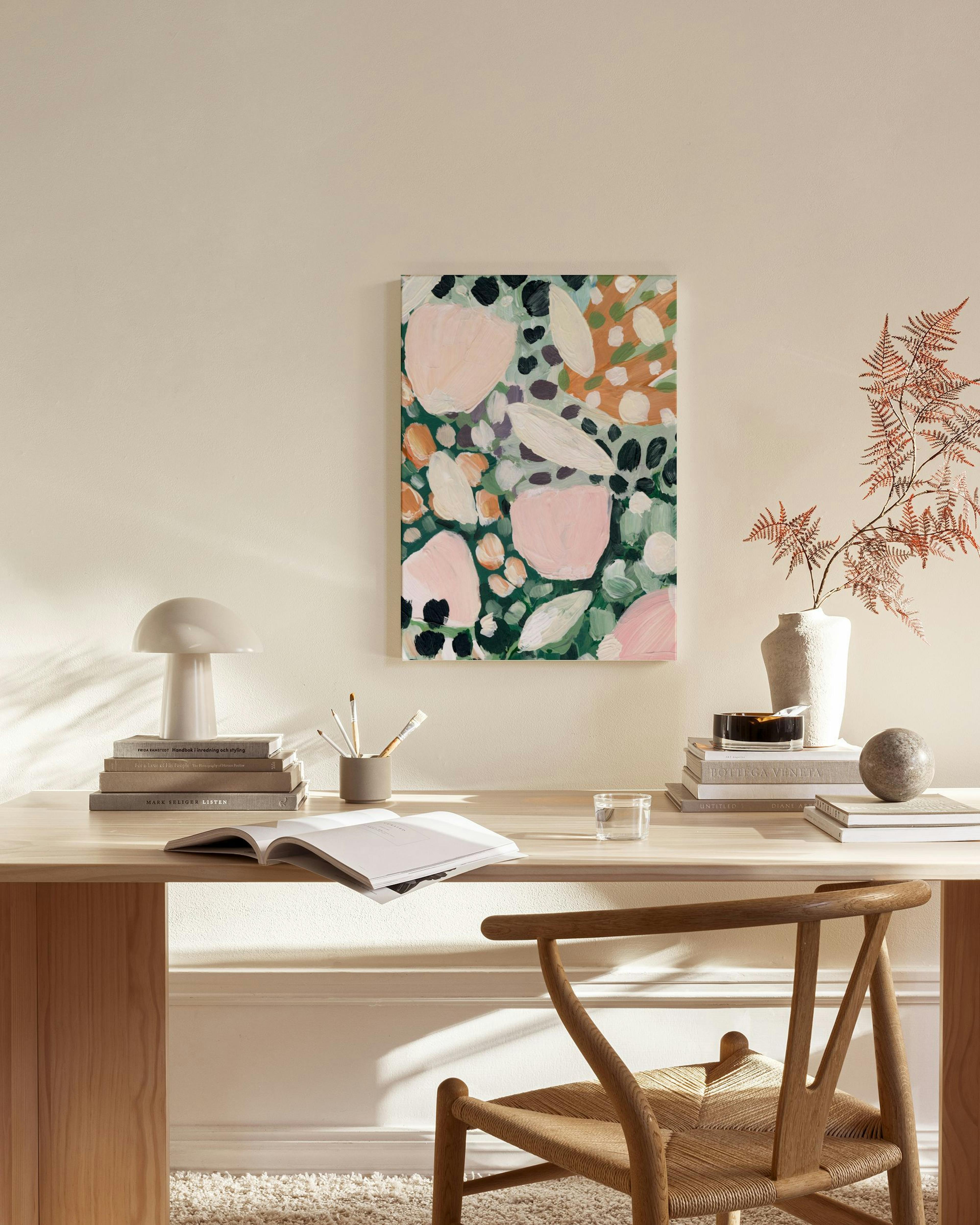 Obraz na plátne s ružovými, zelenými a oranžovými organickými tvarmi na krémovej stene nad drevenou lavicou v obývačke.
