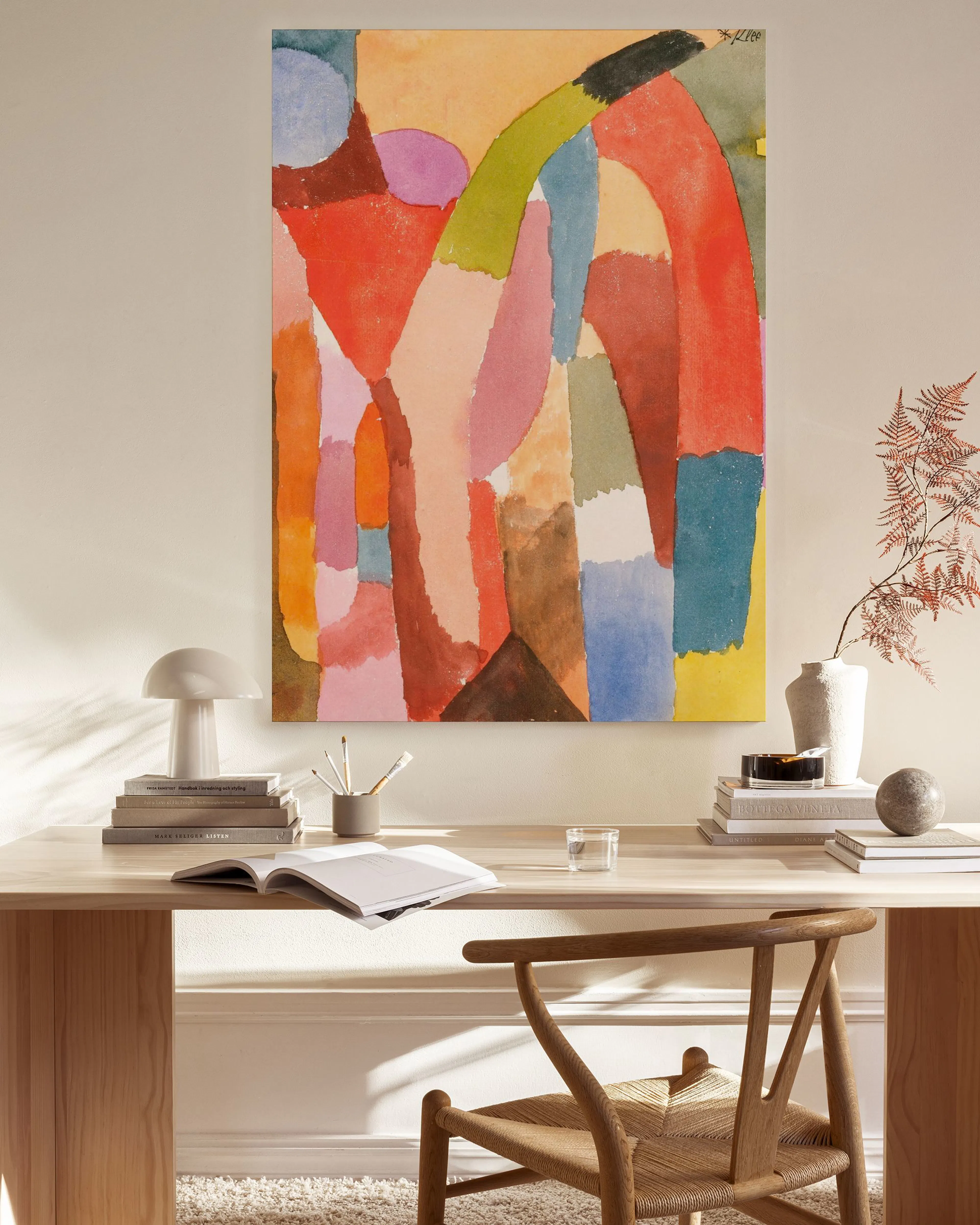 Lienzo abstracto con formas orgánicas y bloques de color en tonos terracota, rojo, verde y azul, colgado en una sala de estar.