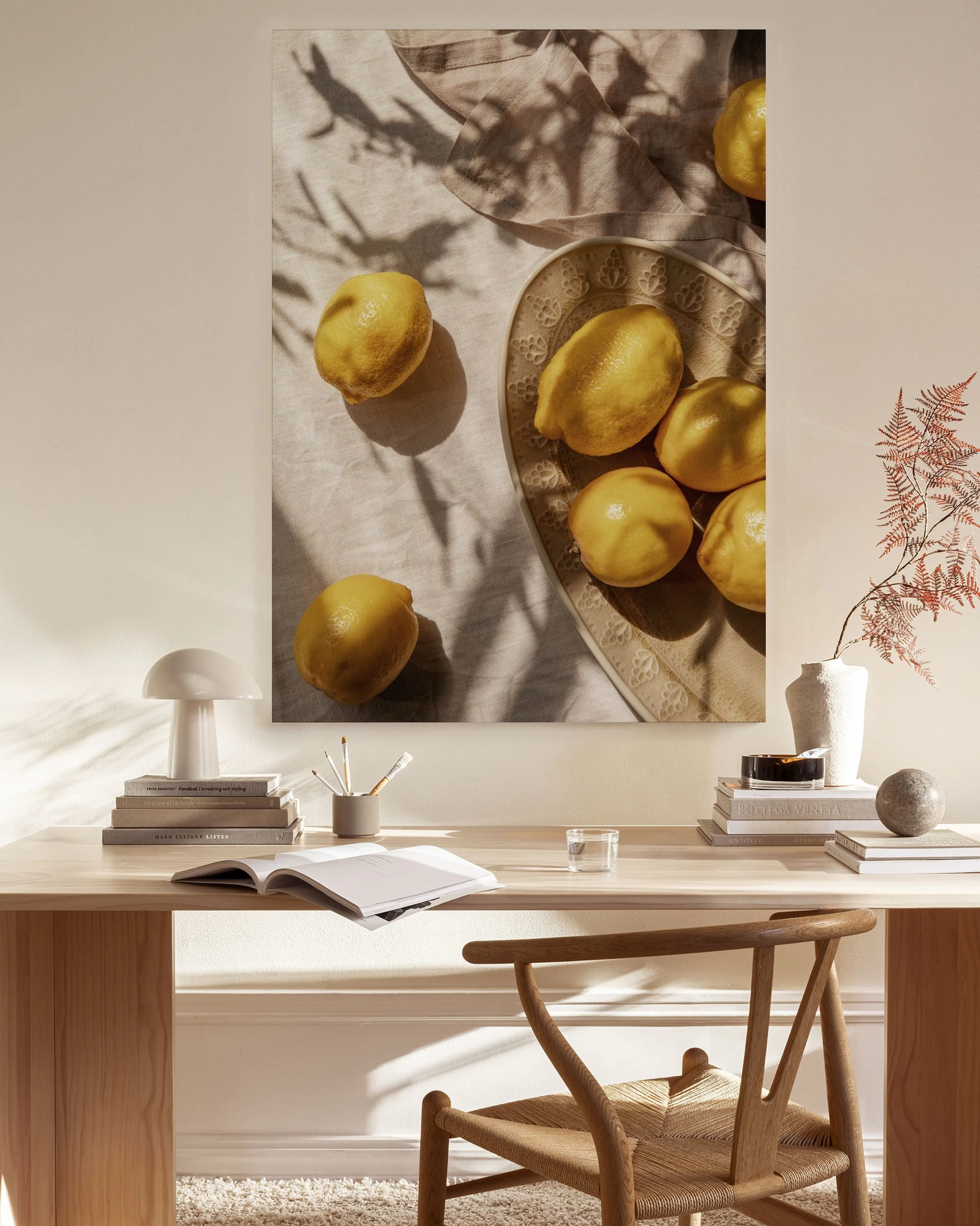 Stampa su tela con limoni su vassoio, appesa in un soggiorno moderno con poltrona in legno.