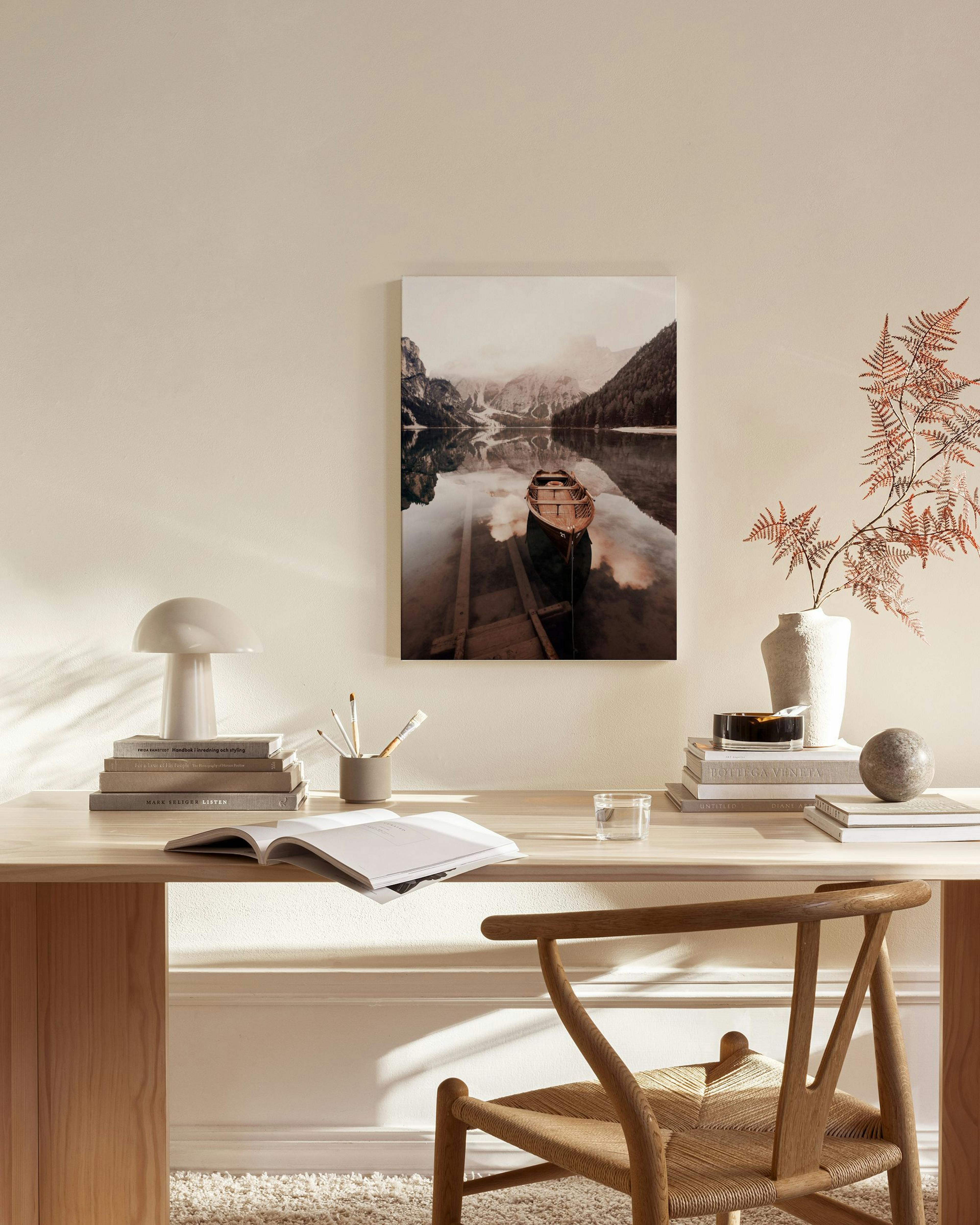 Toile dun lac de montagne avec une barque, reflétant les sommets enneigés, affichée dans un salon moderne aux tons neutres.