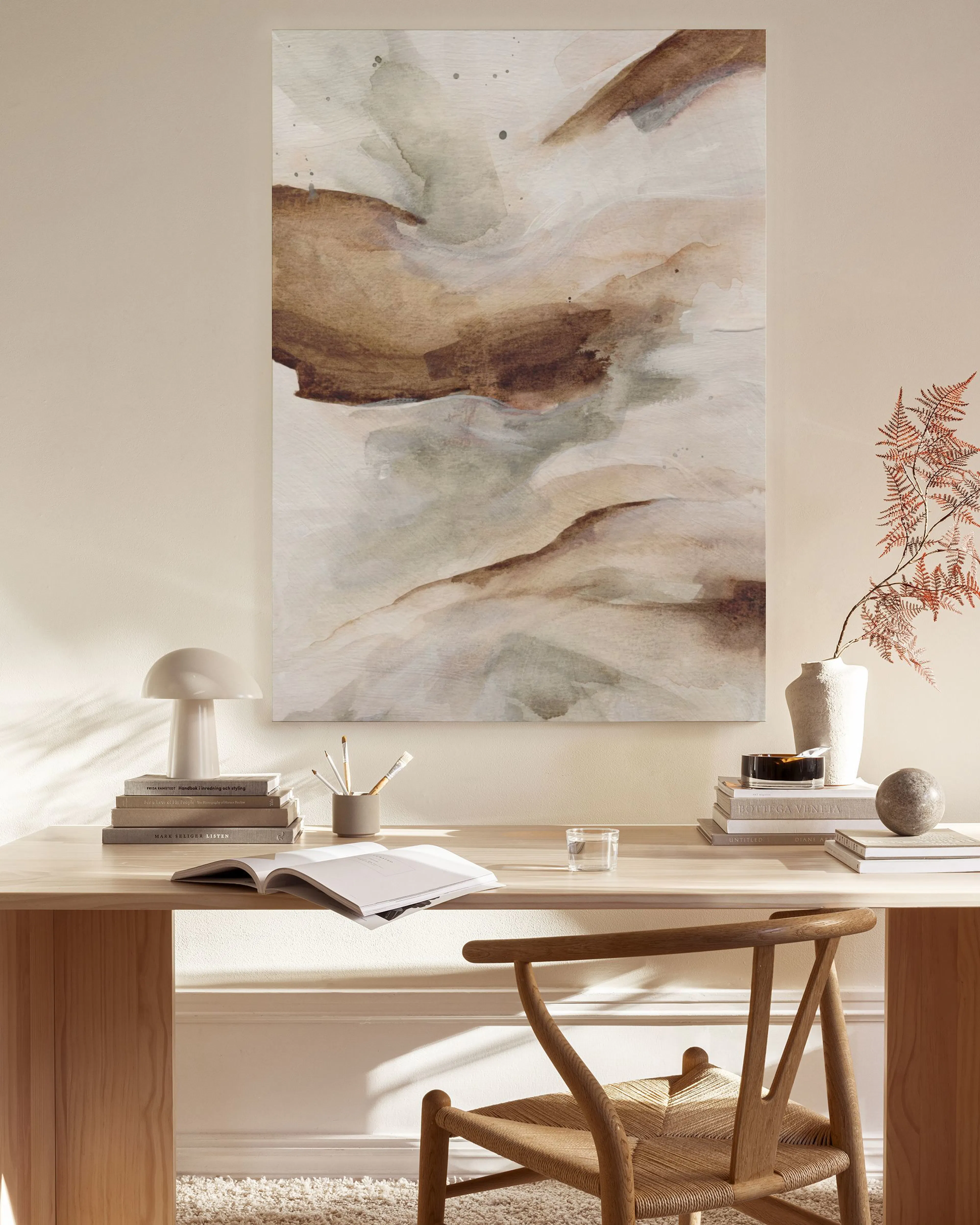 Abstract print with earthy browns, subtle greens, and cream tones, hanging above a wooden console table in a minimalist living r