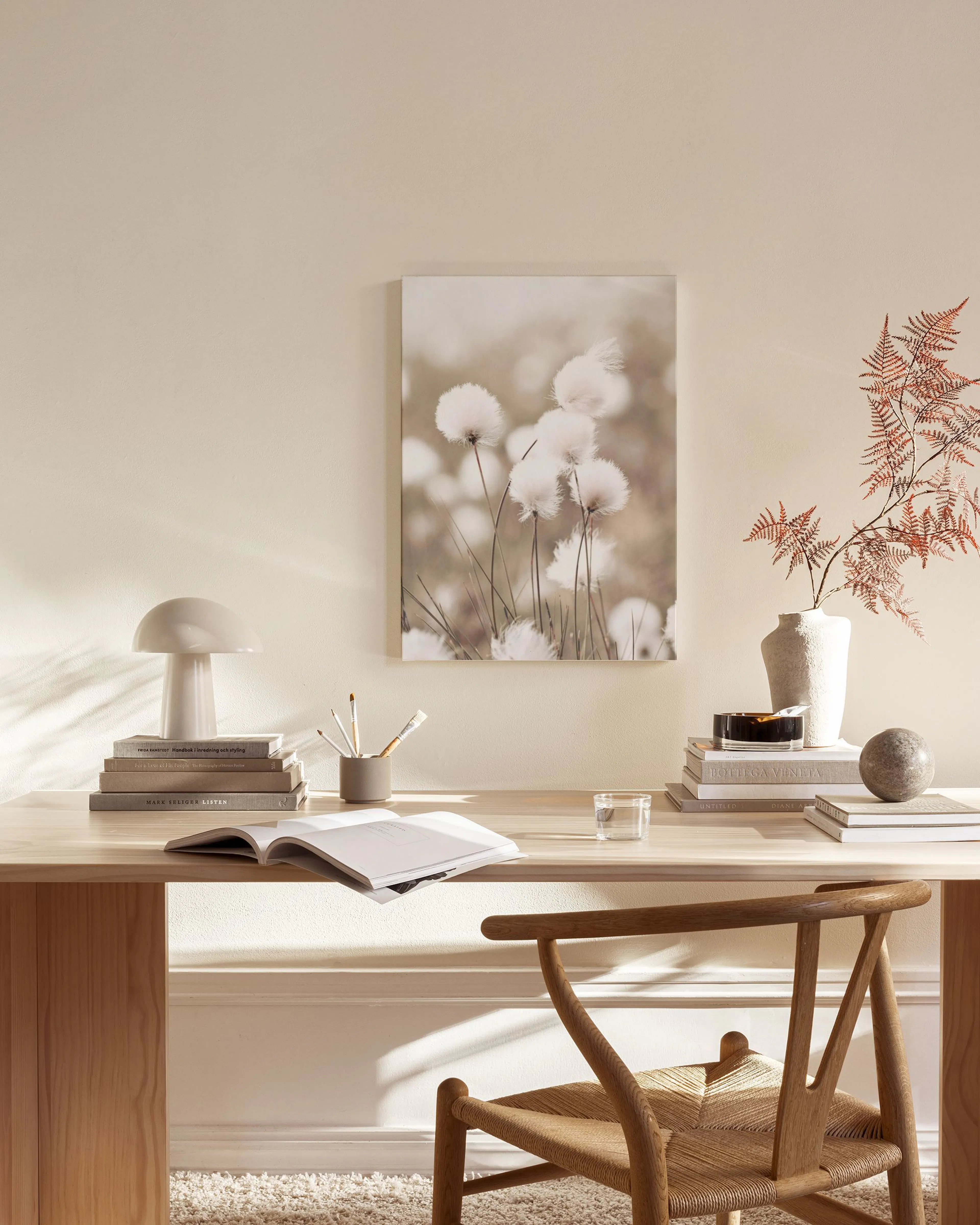 A canvas print of white fluffy cotton grass against a blurred brown background, displayed in a neutral living room.