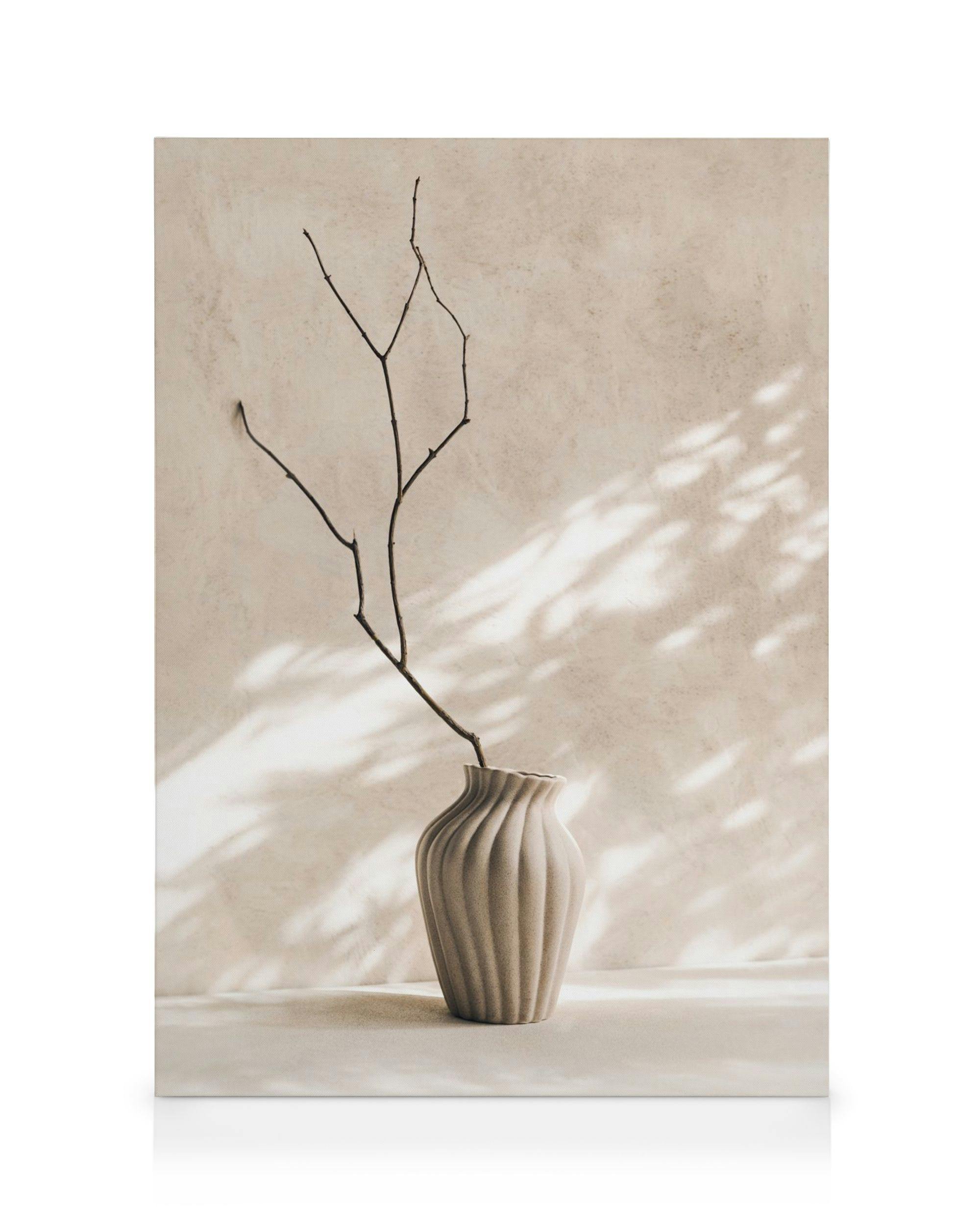 Toile murale minimaliste dun vase beige texturé avec des branches nues et des ombres douces.