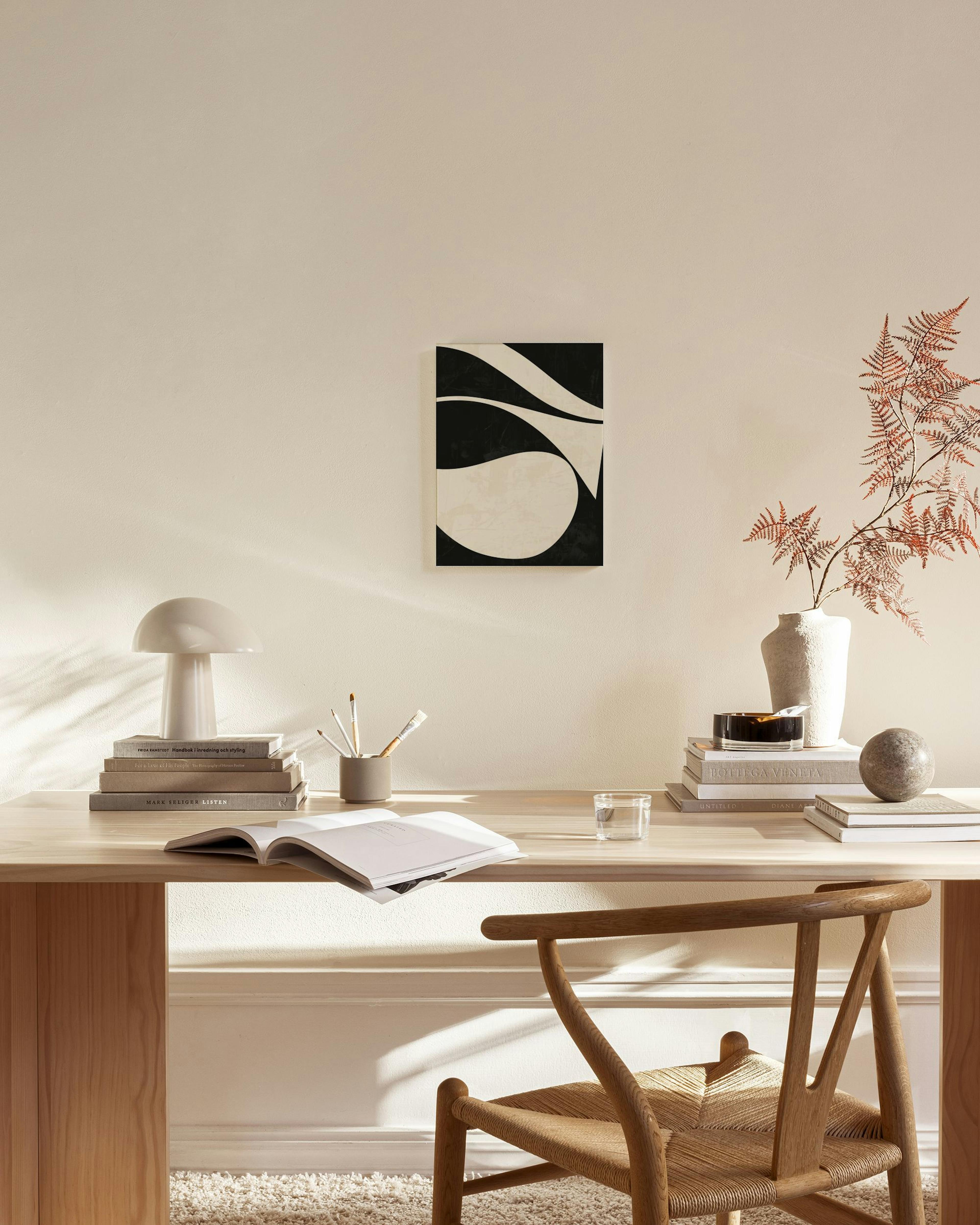 Canvastavla med svarta och beiga vågformade abstrakta former på en strukturerad bakgrund.