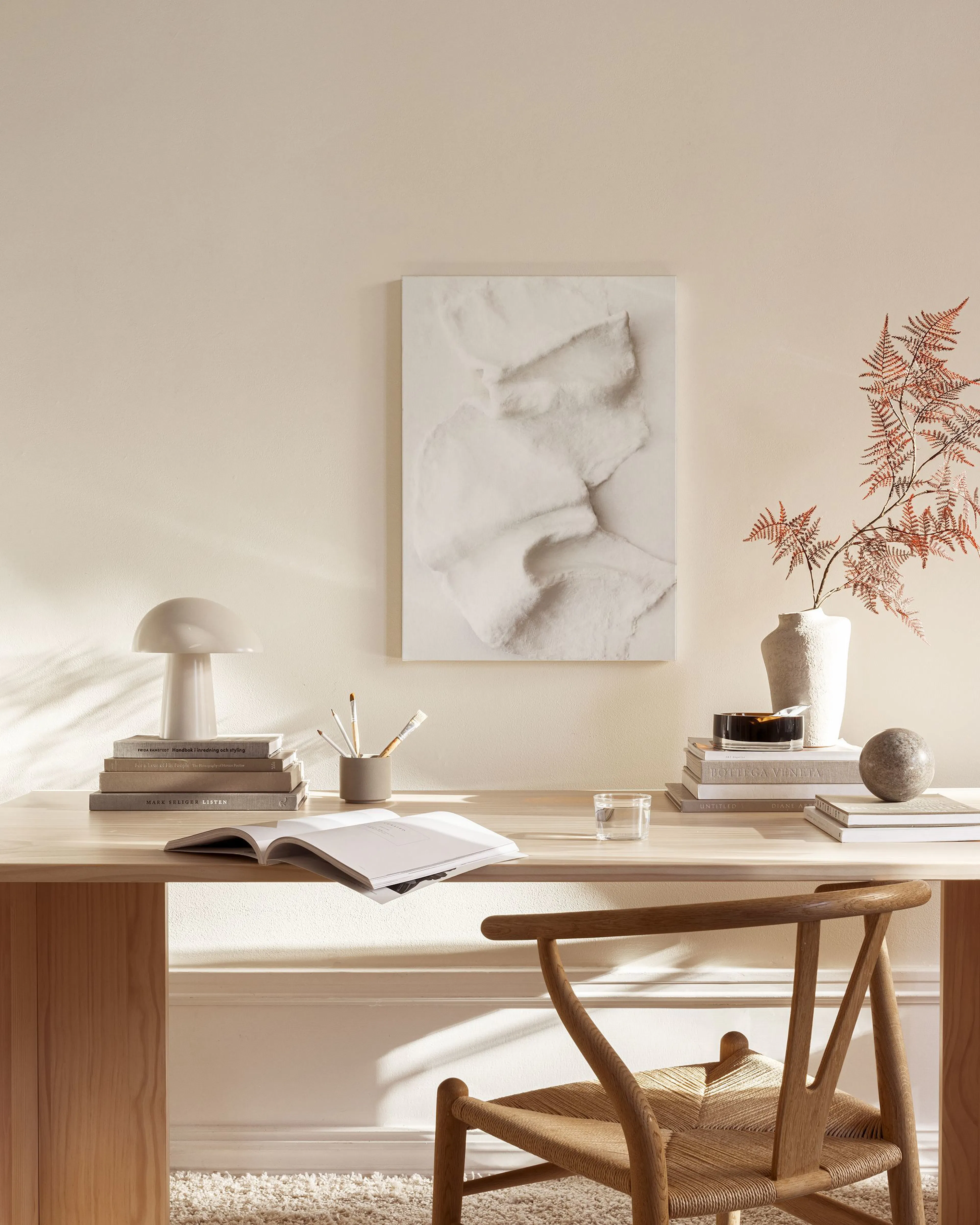 Abstract canvas print with white, textured organic shapes, hanging in a minimalist living room above a wooden console.
