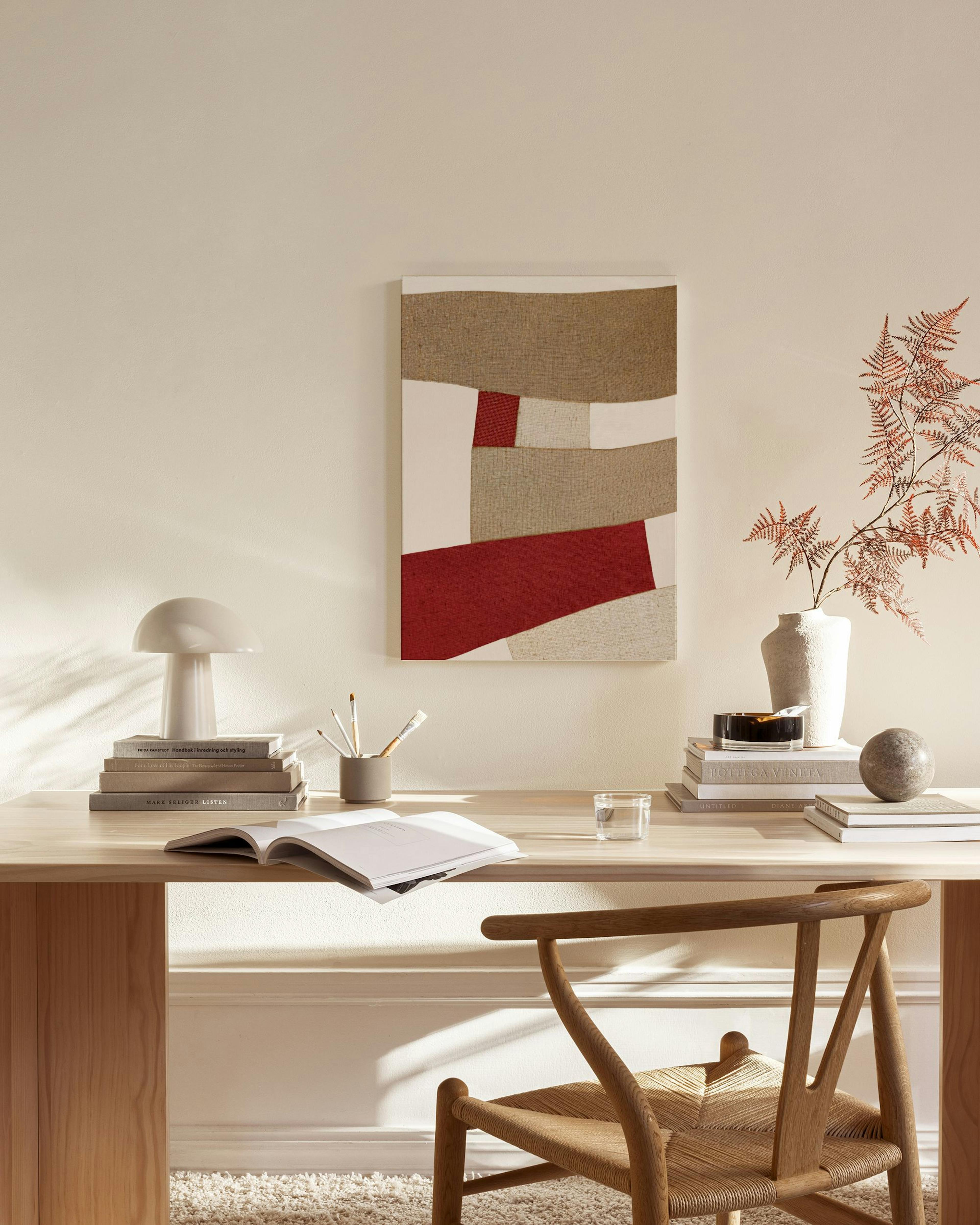 Leinwandbild mit roten, beigen und grauen geometrischen Formen, hängend über einem Sideboard in einem Wohnzimmer.