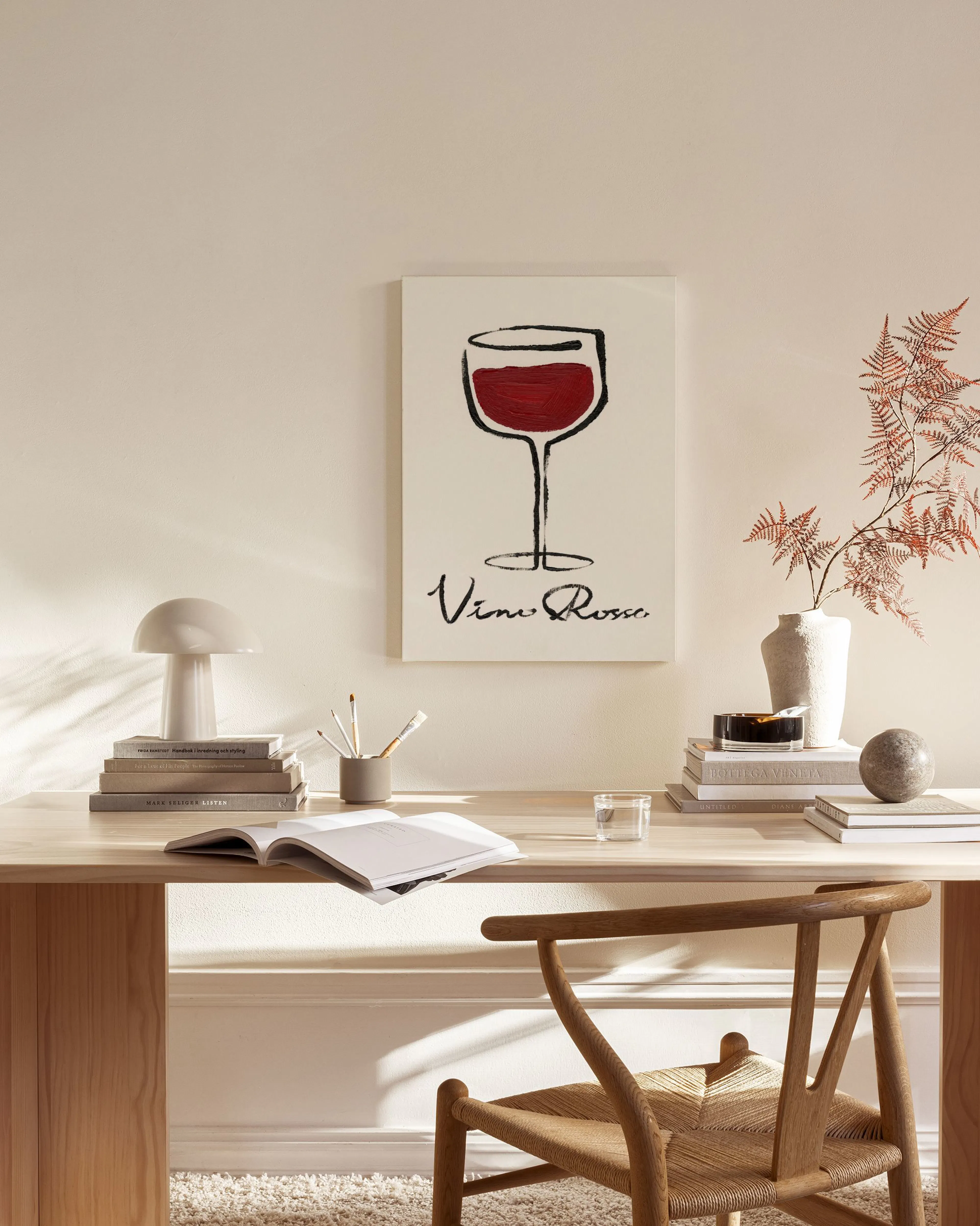 Lærred med illustreret vinglas med rødvin og teksten Vino Rosso, hængende over en træbænk i en stue.