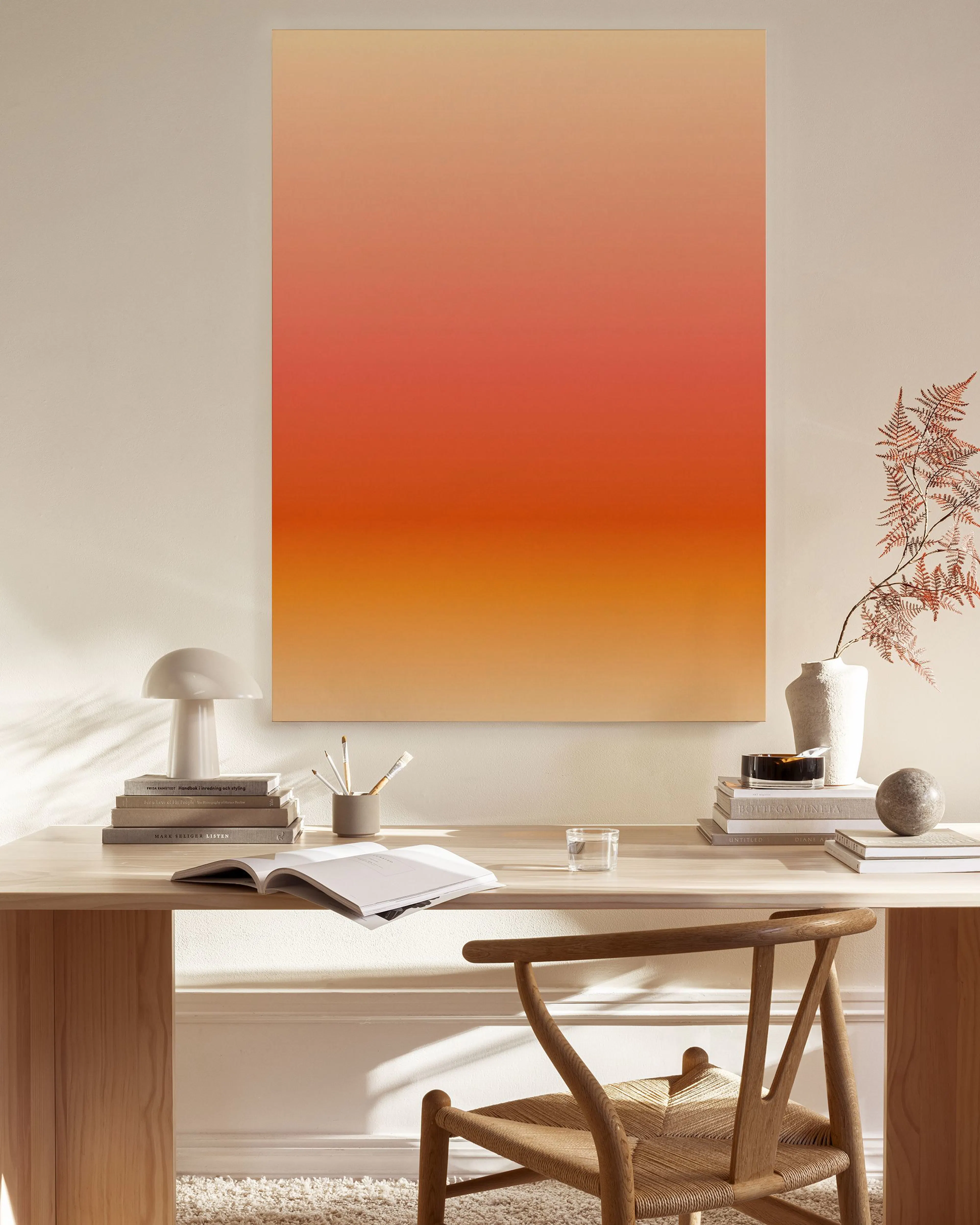 Canvastavla med orange, beige och röd gradient, hängande i ett modernt vardagsrum.