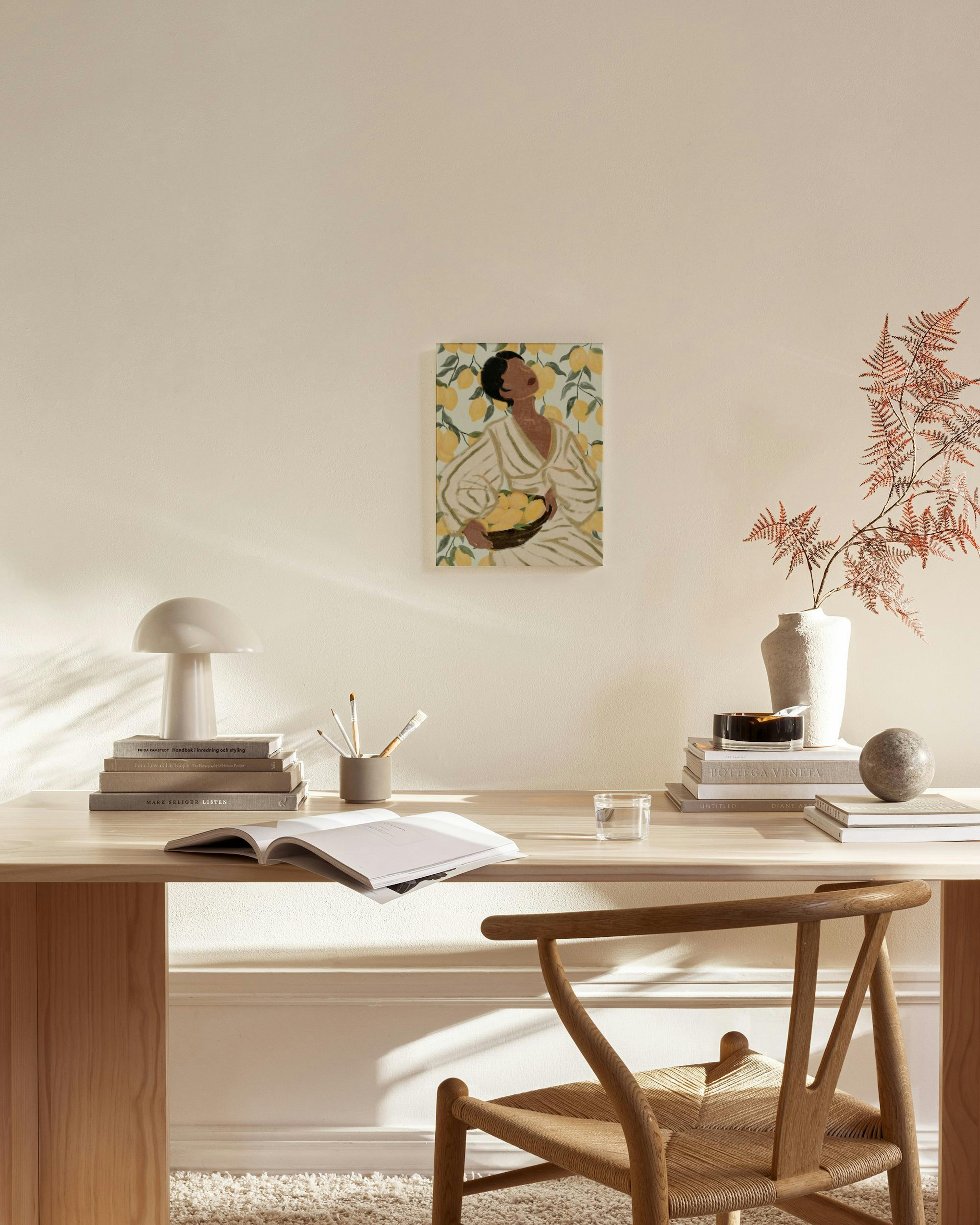 Lienzo de una mujer sosteniendo una cesta de limones en un fondo de árboles de limón, colgado en una sala de estar moderna.