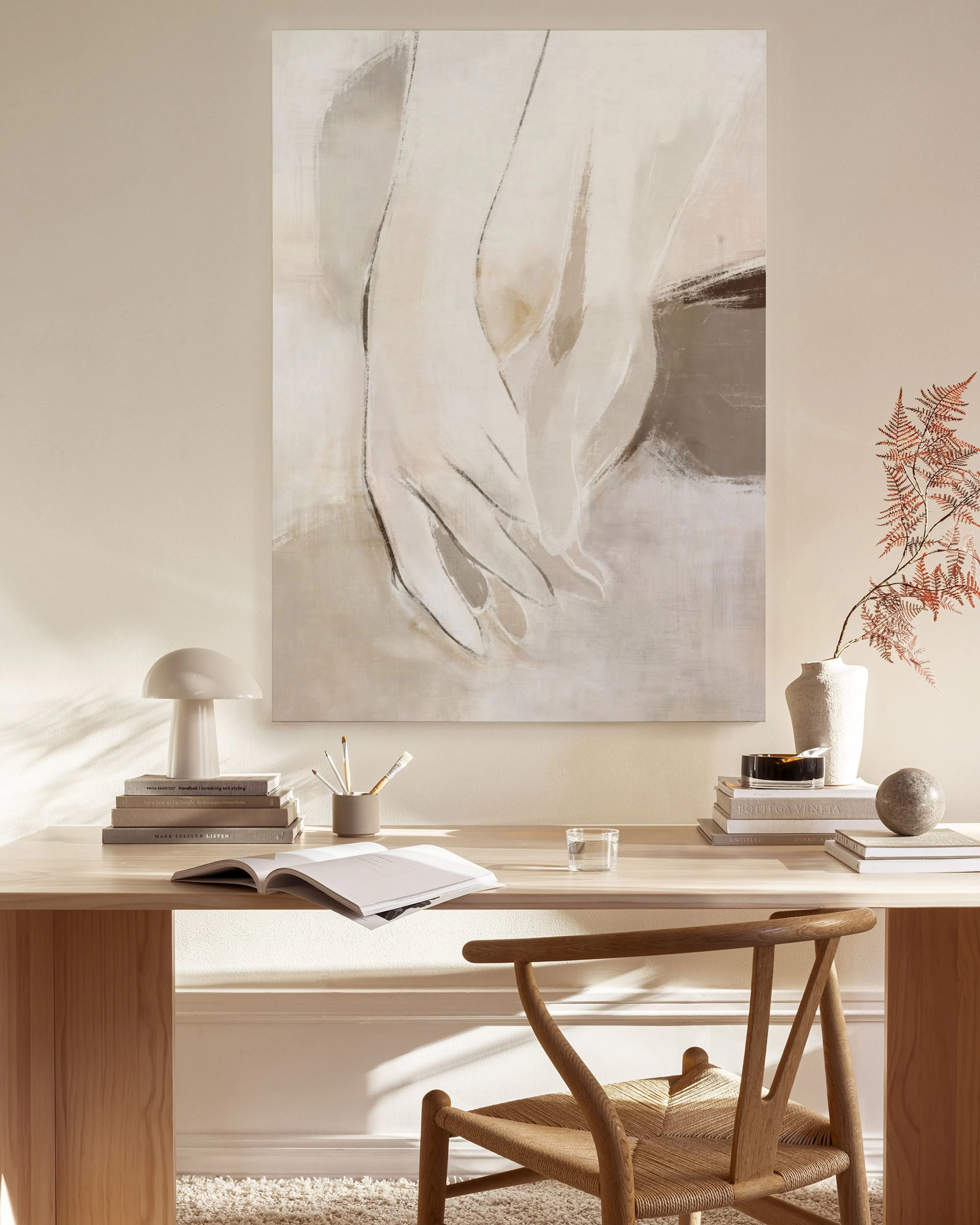 Toile abstraite tons neutres de beige et marron, des mains stylisées, exposée dans un salon moderne.