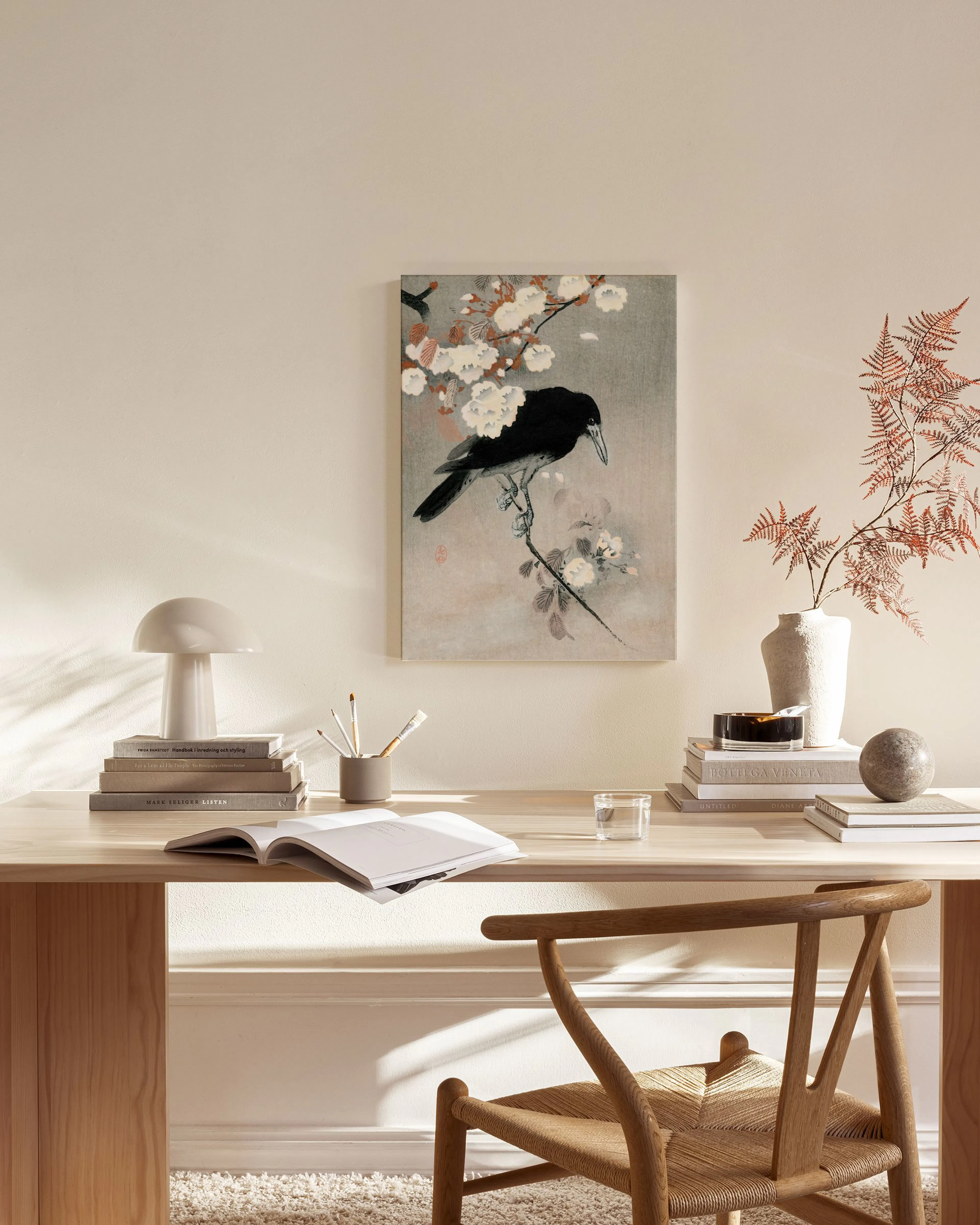 Japanese art canvas print of a black crow perched on a branch with white blossoms, hanging in a minimalist living room.