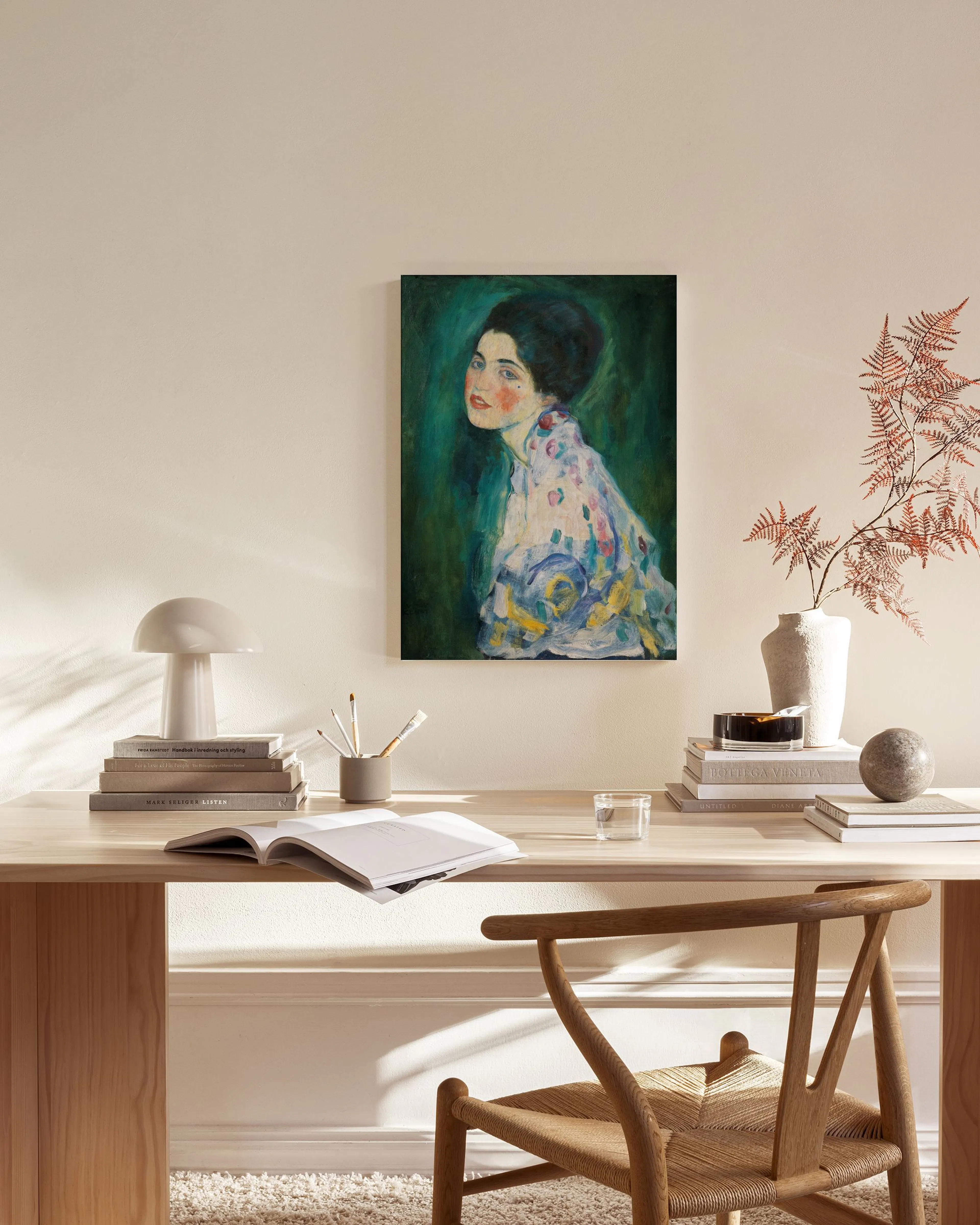 Toile de femme aux cheveux noirs sur fond vert émeraude, vêtue dune robe fleurie, dans un salon moderne.