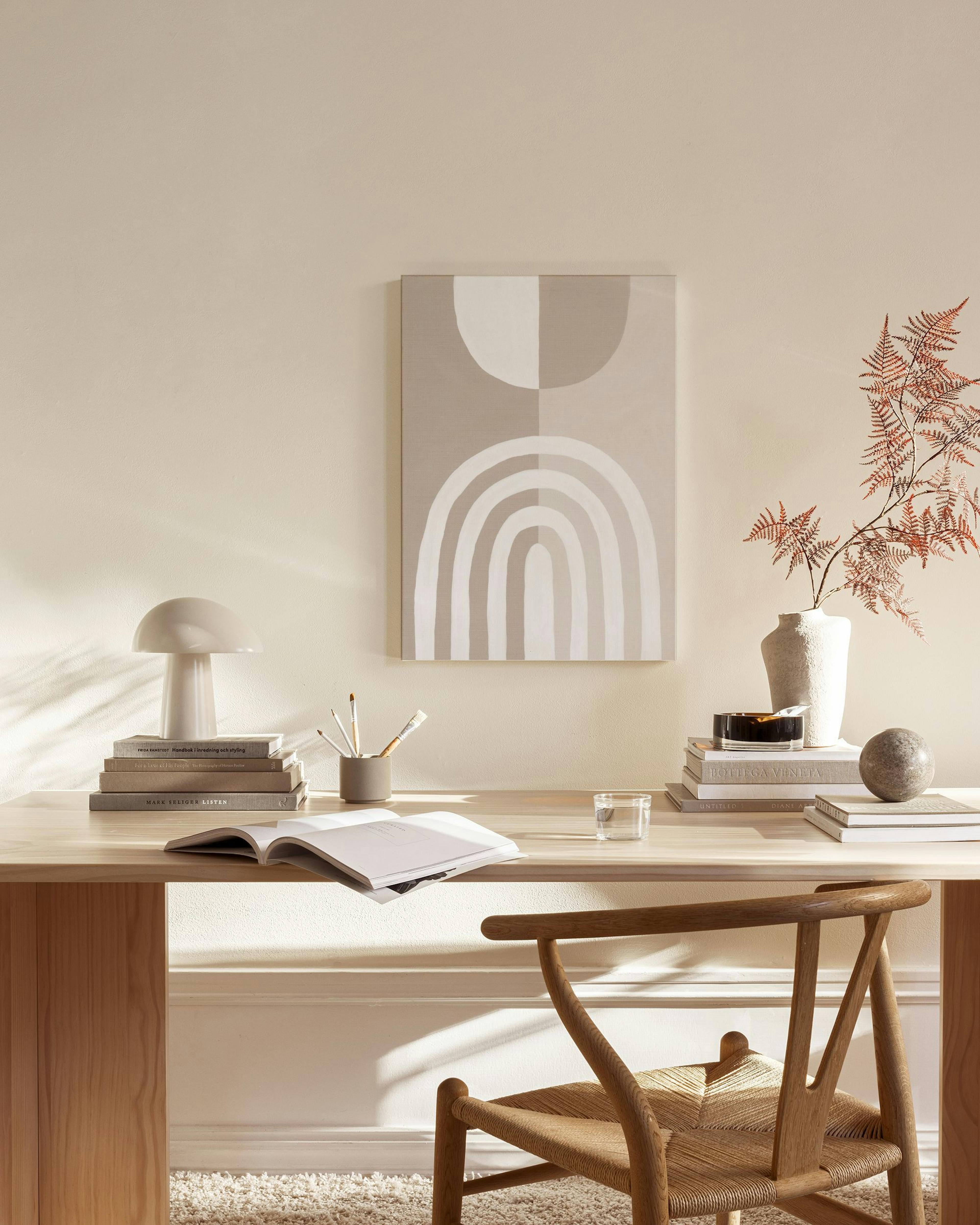 Leinwandbild mit hellem Bogenmotiv und Kreisen in Beige und Weiß, hängend über einem Sideboard in einem Wohnzimmer.