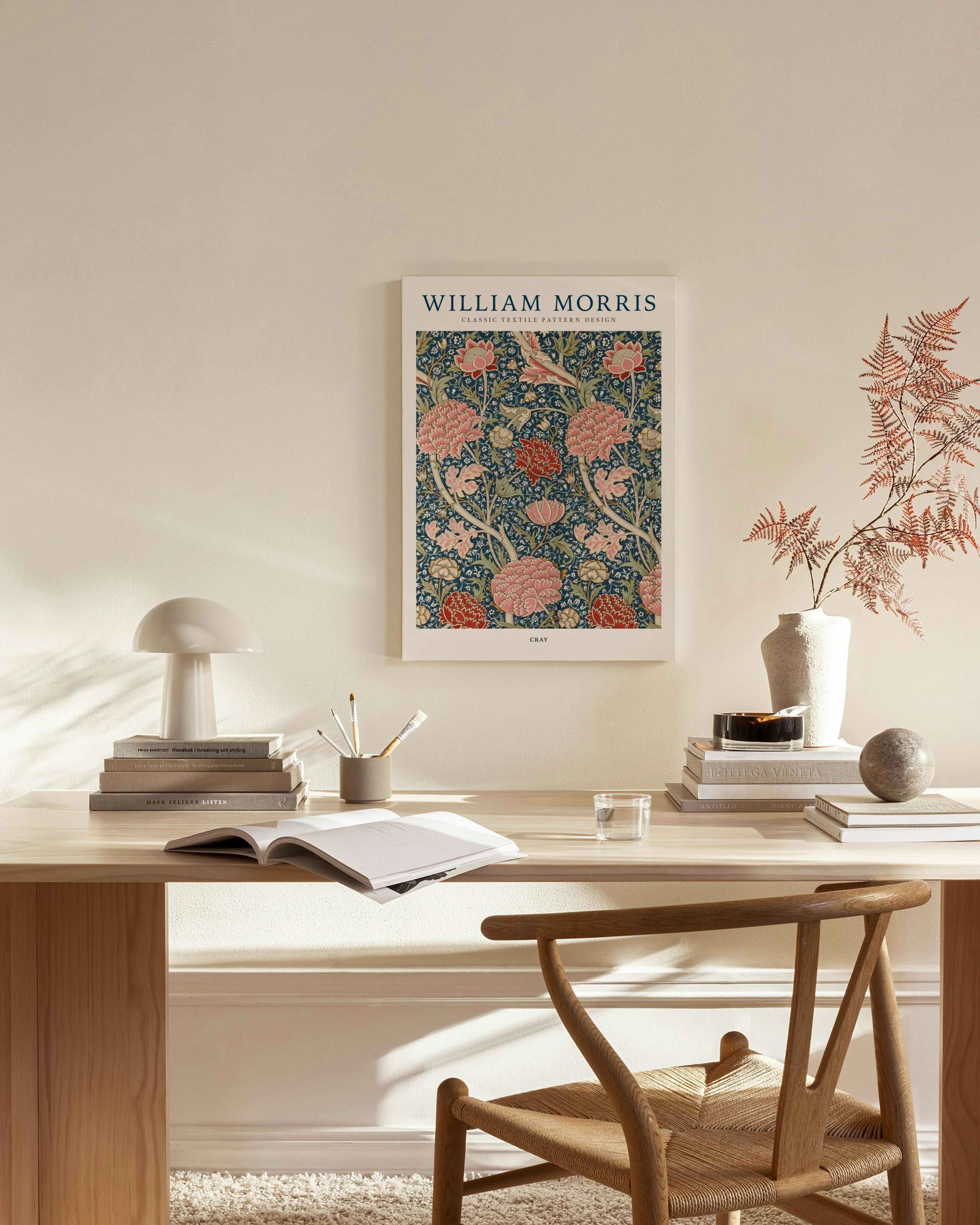 A William Morris art nouveau floral print with red and pink flowers on dark blue, hanging in a modern living room.