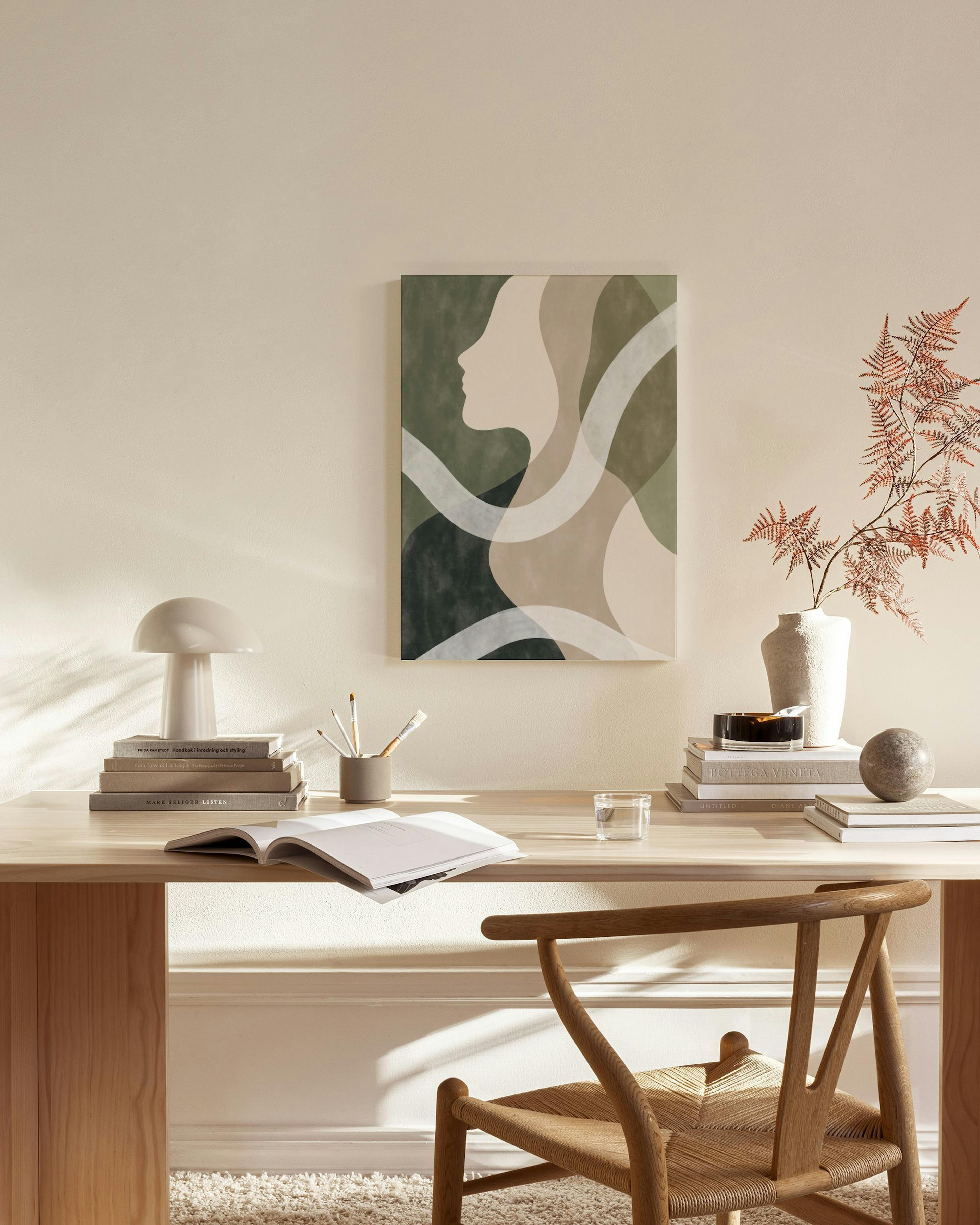 Canvastavla med kvinna i profil, gröna och beiga toner, och vita slingor, hängandes i ett ljust vardagsrum.