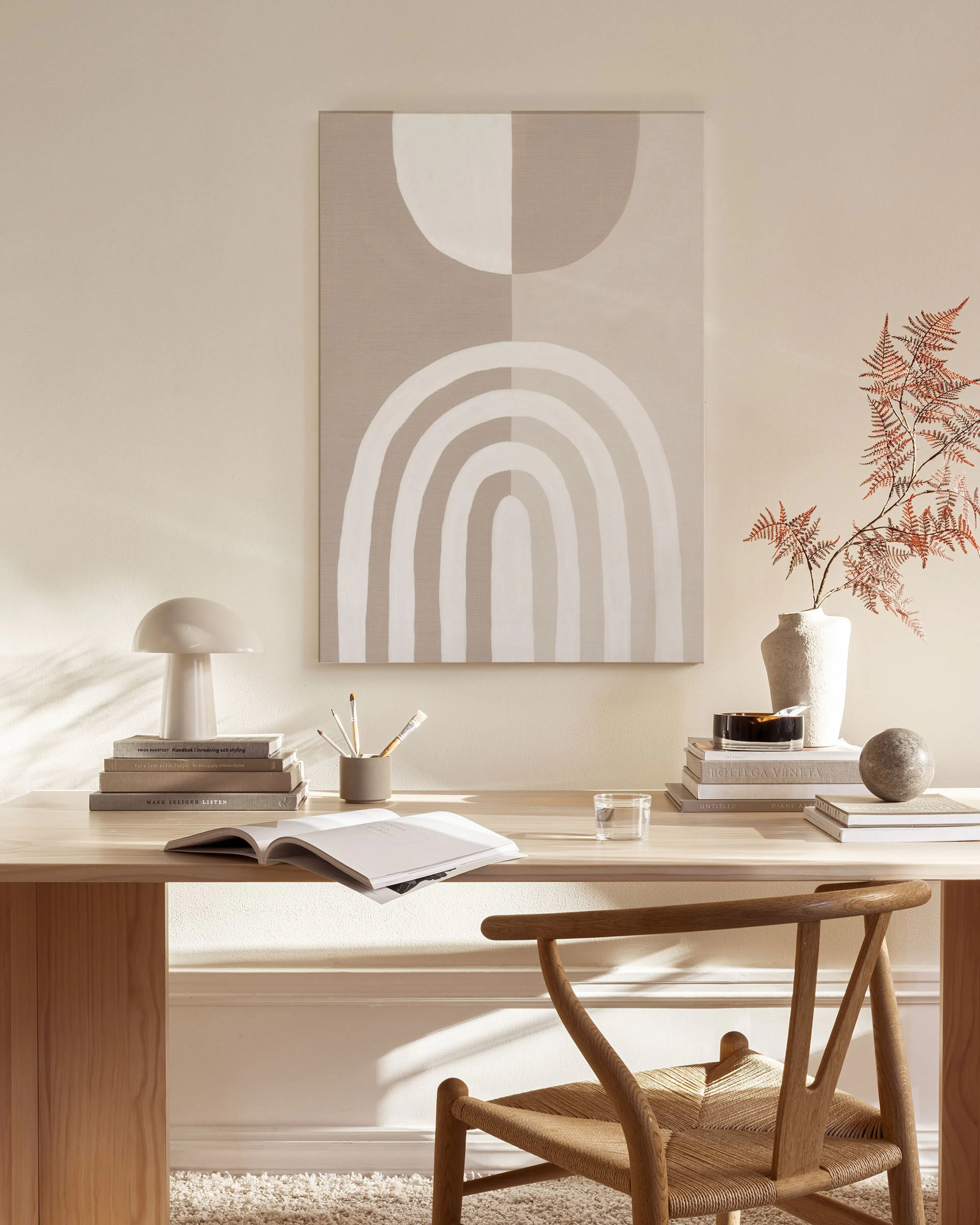 Tela decorativa com formas geométricas abstratas em bege e branco, suspensa numa sala de estar minimalista com mobiliário de mad