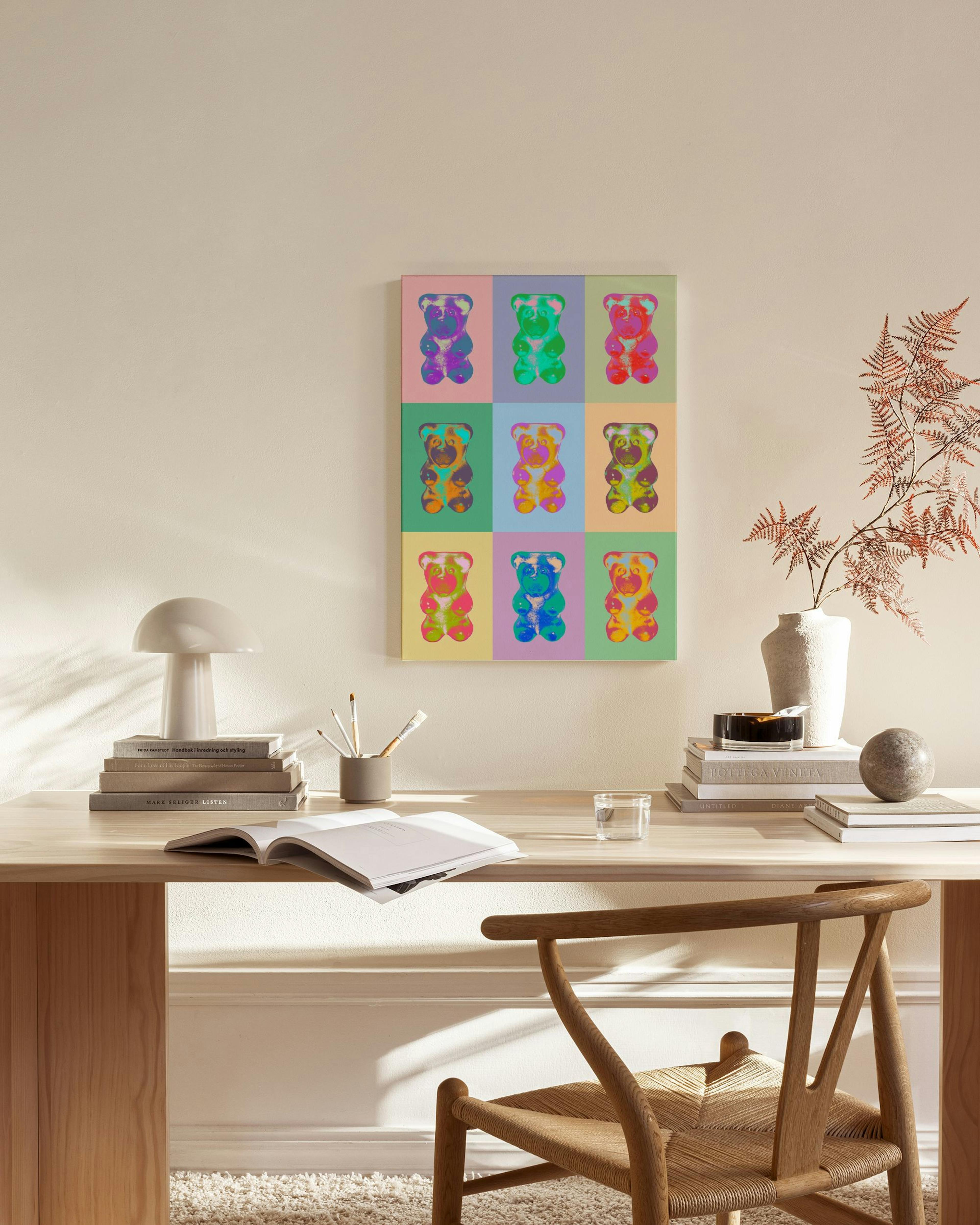Canvastavla med färgglada nallebjörnar i popkonststil, hängande i ett ljust vardagsrum med trädetaljer.