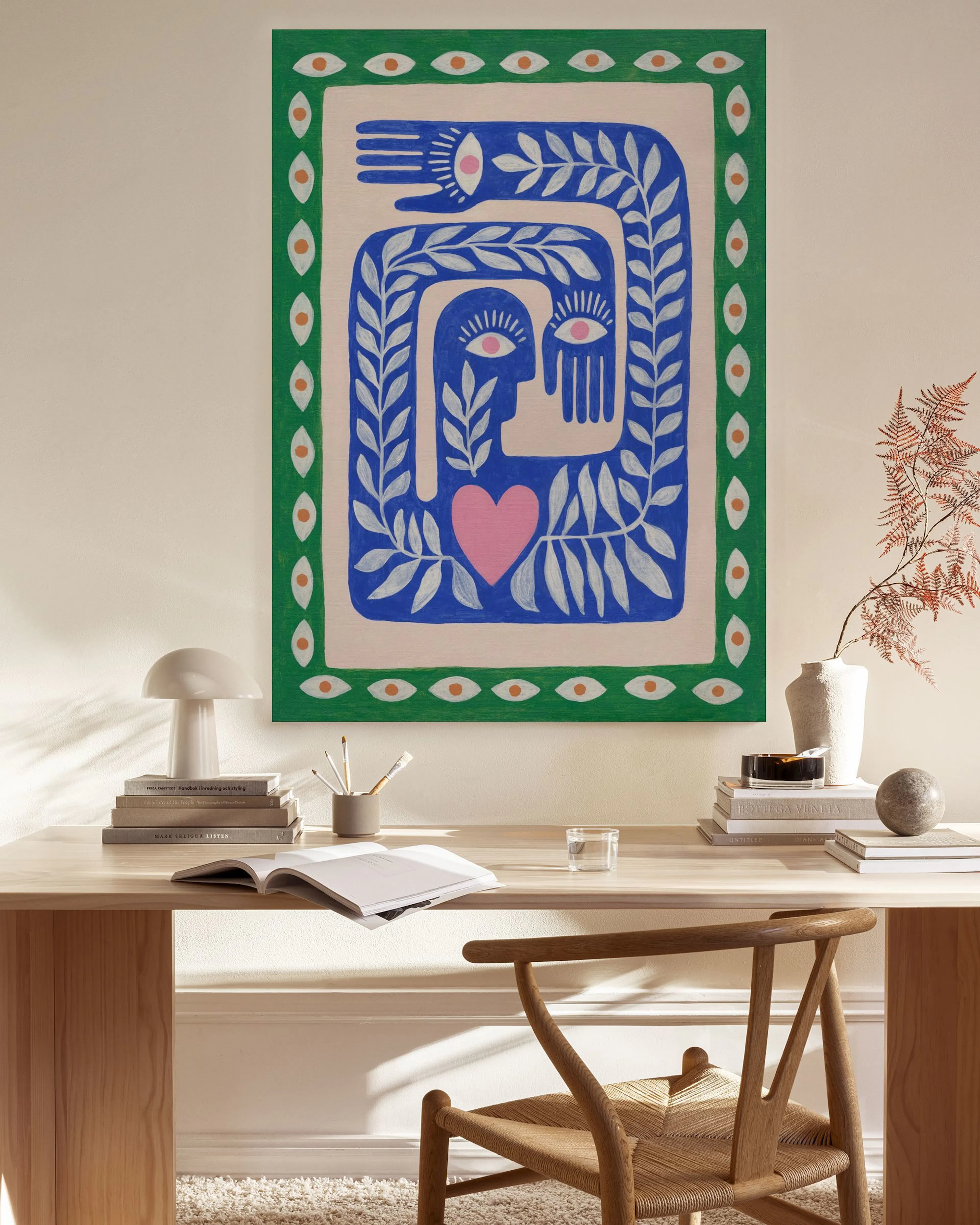 Leinwandbild mit abstraktem Design aus blauen, grünen und rosa Formen, das in einem hellen Wohnzimmer über einer Holzbank hängt.