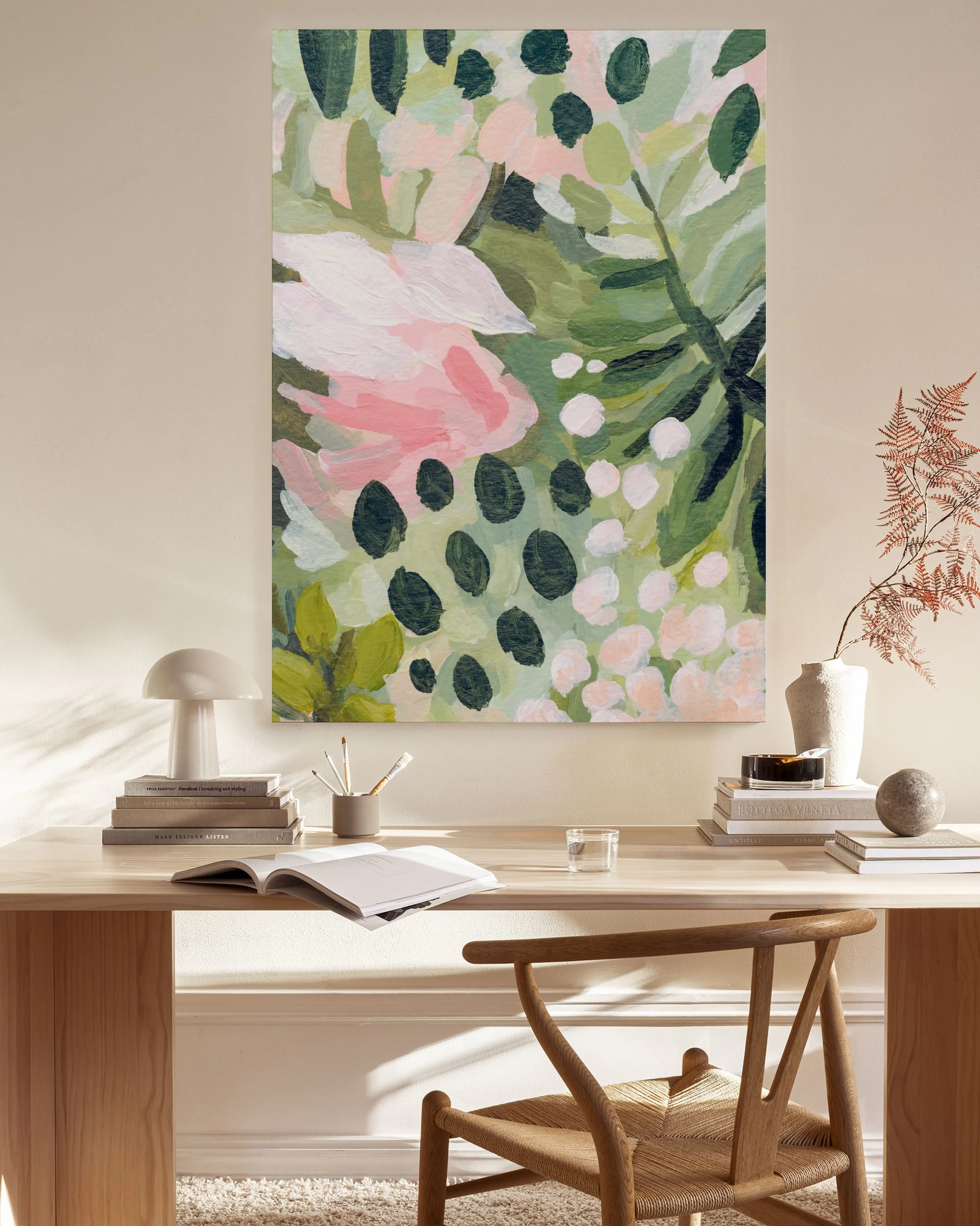 Leinwandbild mit pastellfarbenen Blättern und rosa Blüten, hängend über einem Sideboard in einem modernen Wohnzimmer.
