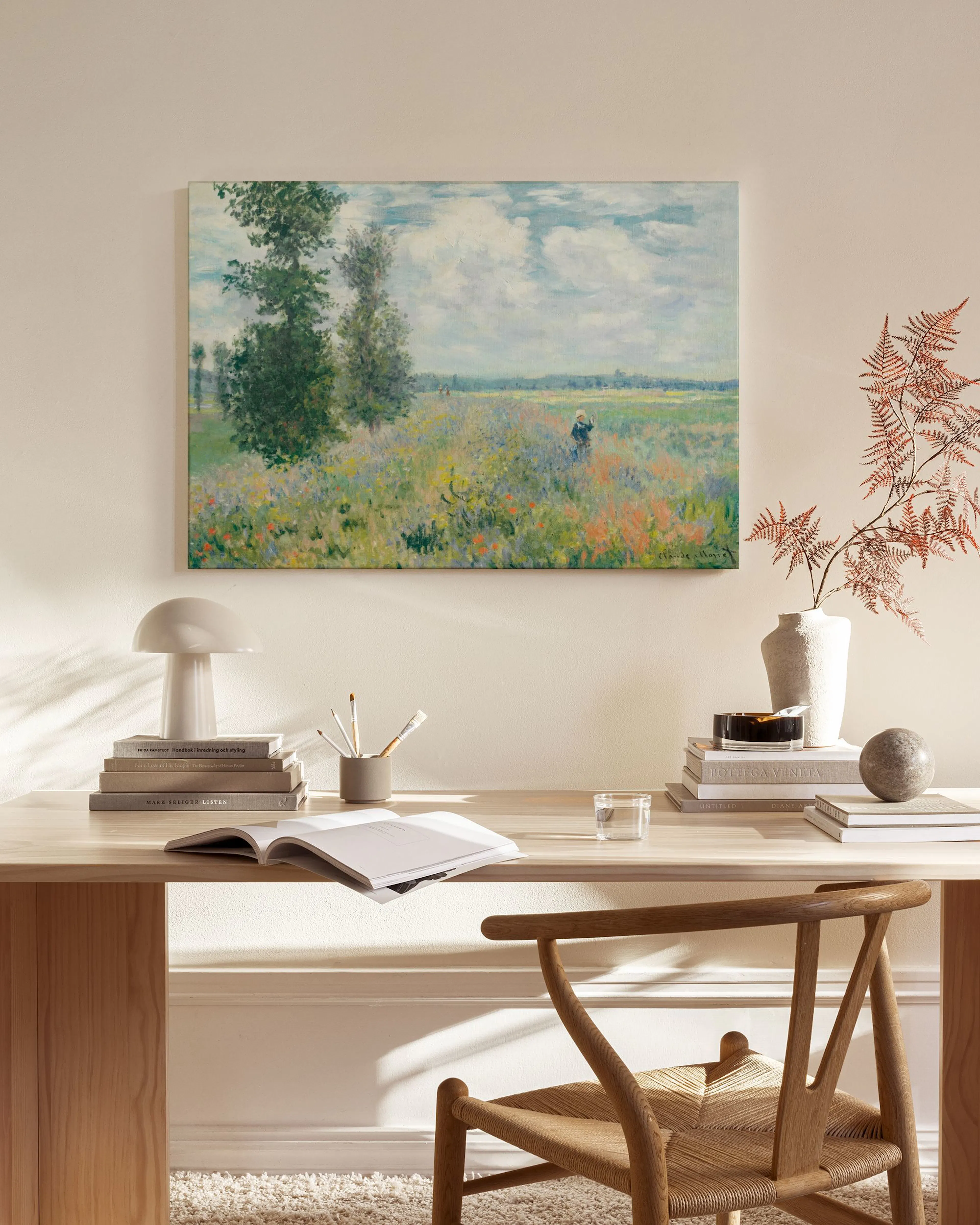 Lærred med et impressionistisk maleri af et blomstrende marklandskab, ophængt over et træmøbel i en stue.