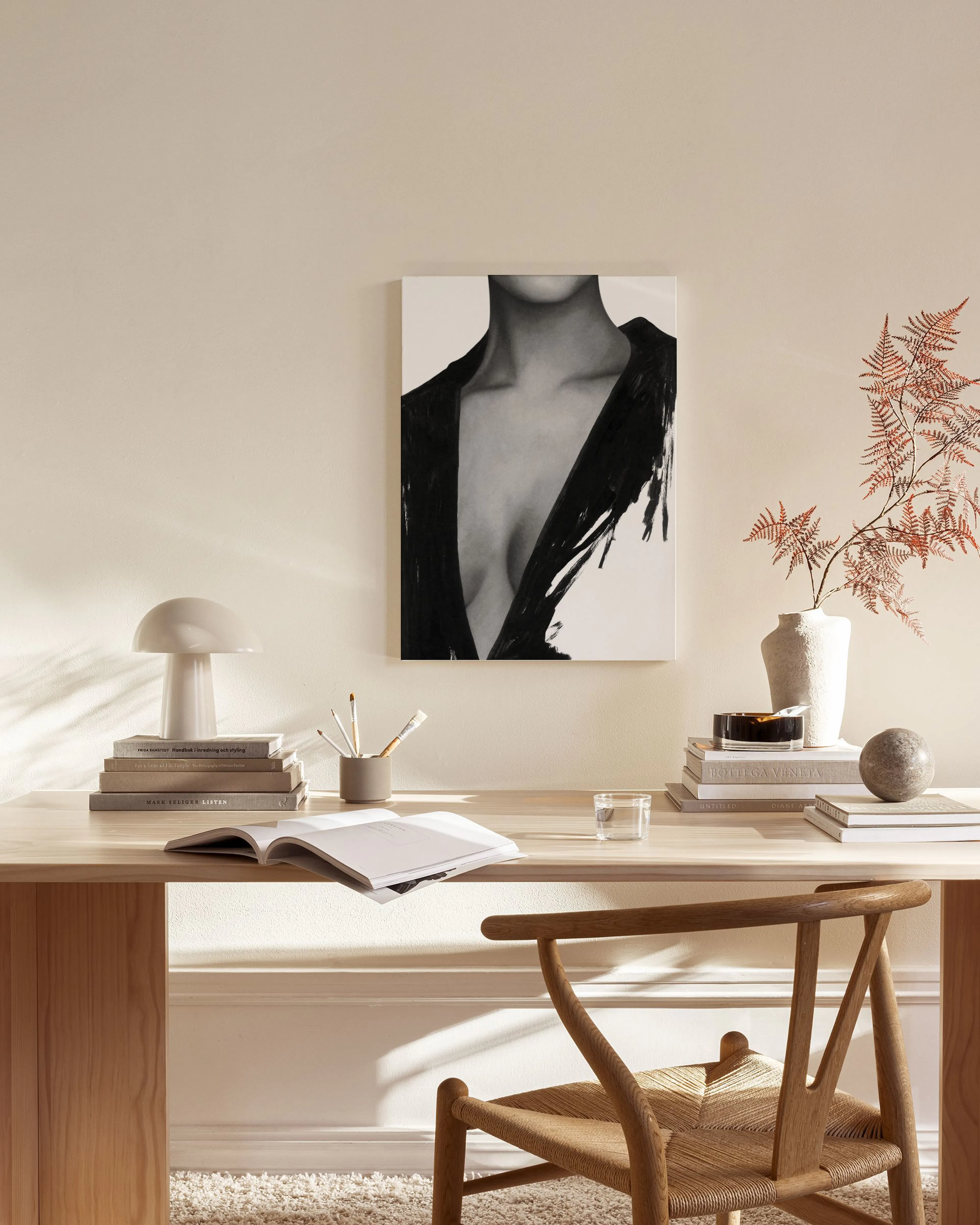 A black and white canvas print depicting a womans torso in a dark, open jacket, hanging in a minimalist living room.