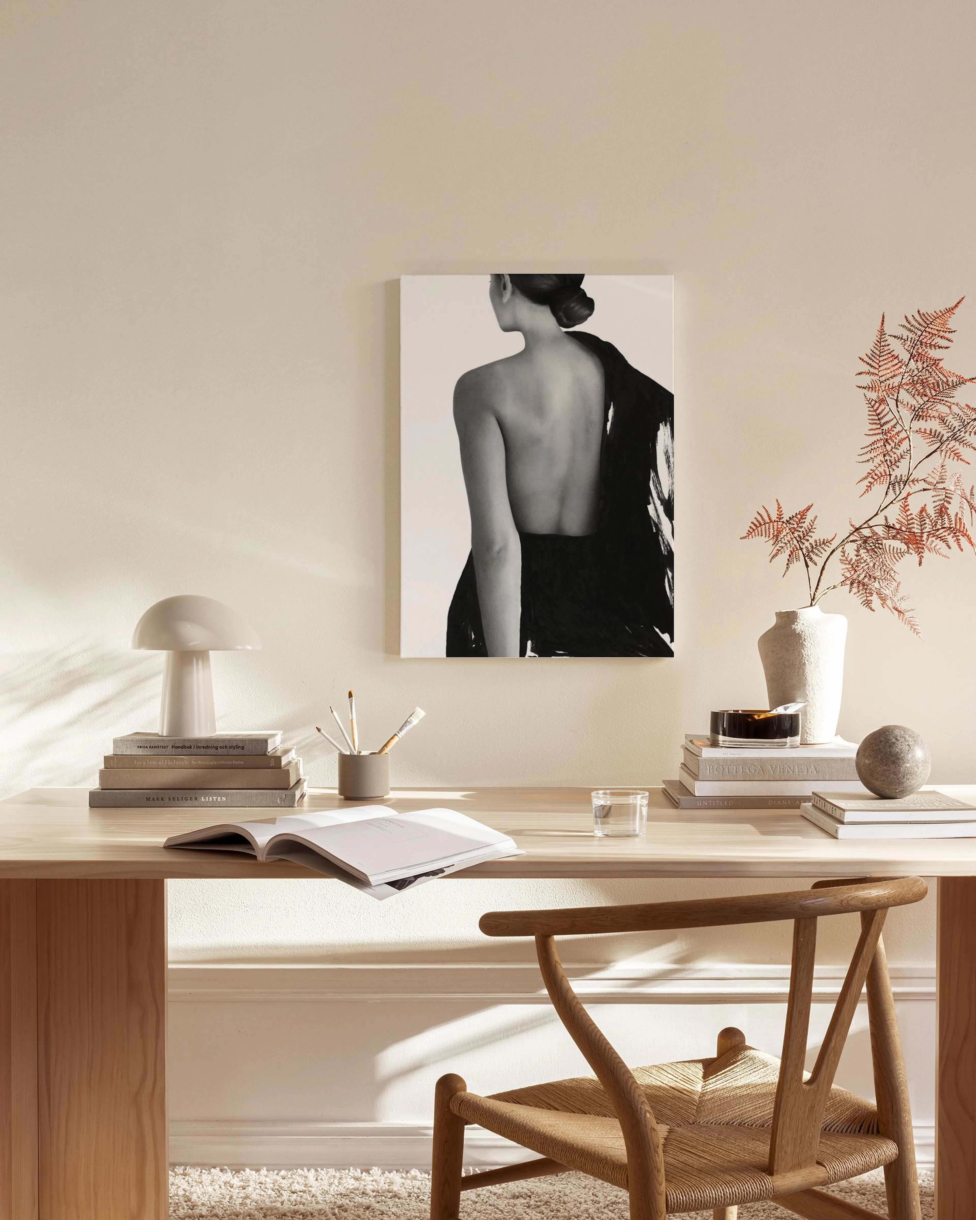 Leinwandbild einer Frau in Schwarz-Weiß mit freiem Rücken, hängend in einem modernen Wohnzimmer über einem Sideboard.