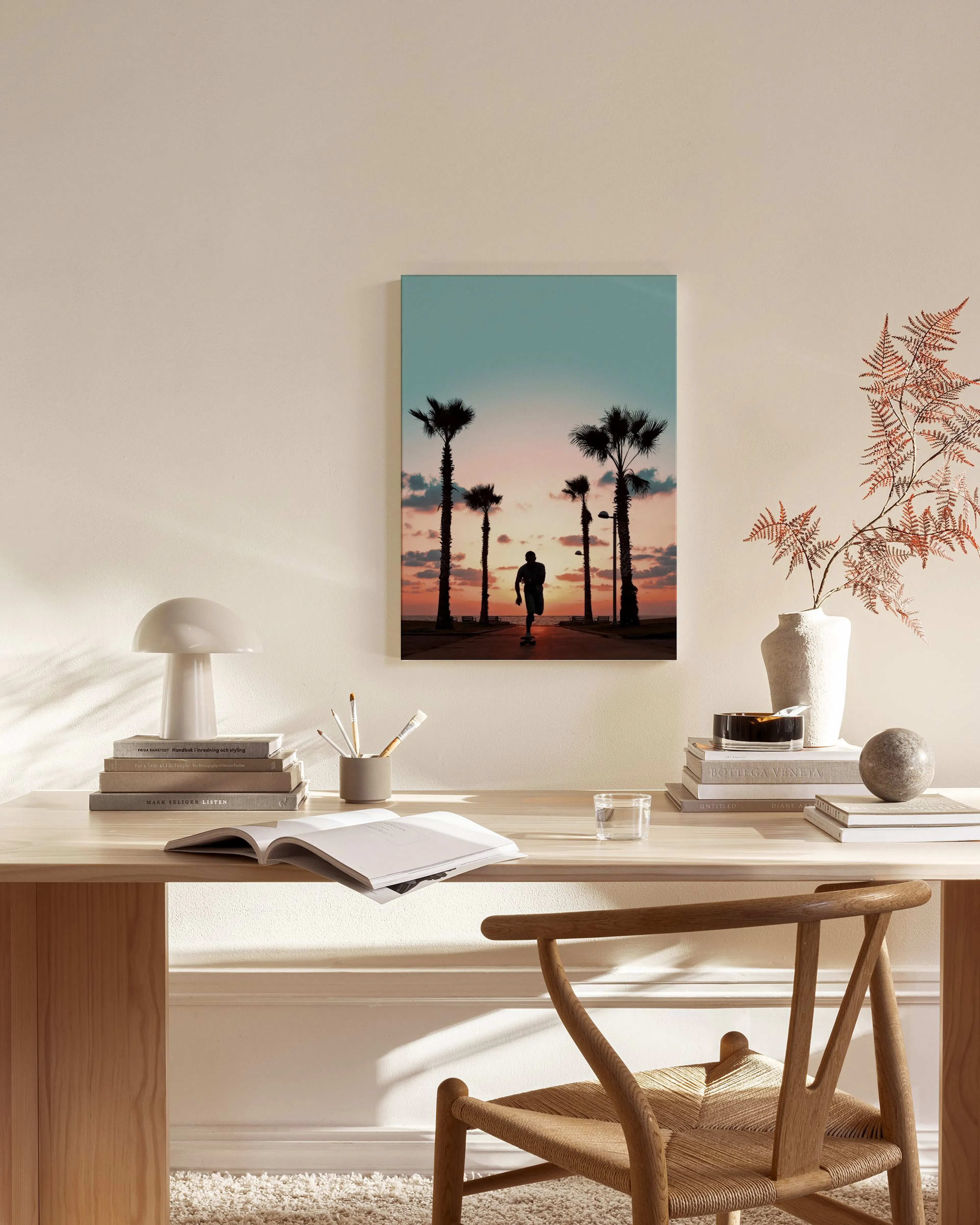 Leinwandbild mit Palmen und einer Person bei Sonnenuntergang, hängt über einem Sideboard im Wohnzimmer.