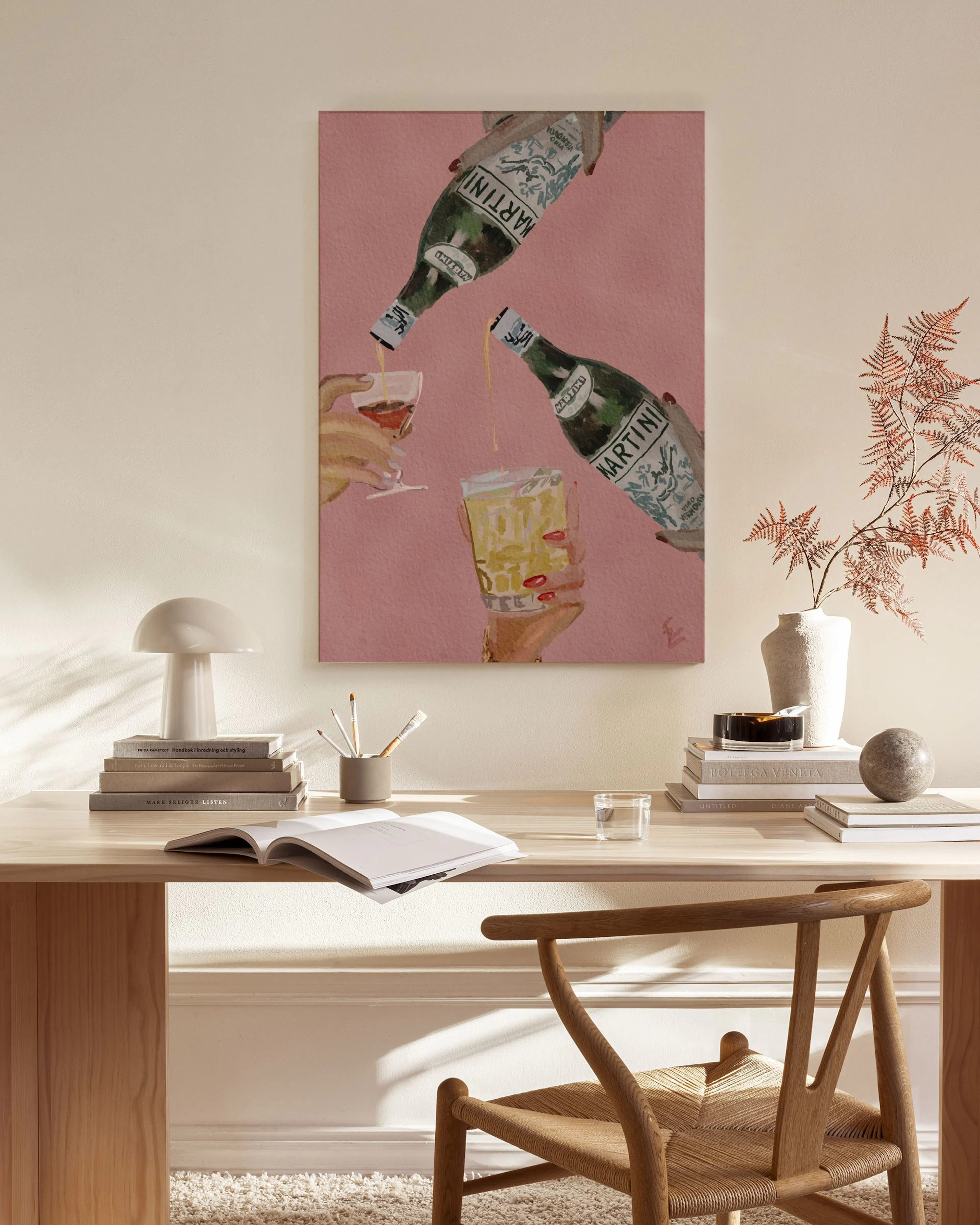 Canvas van twee Martini-flessen die drank in glazen schenken op een roze achtergrond, hangend in een neutrale woonkamer.