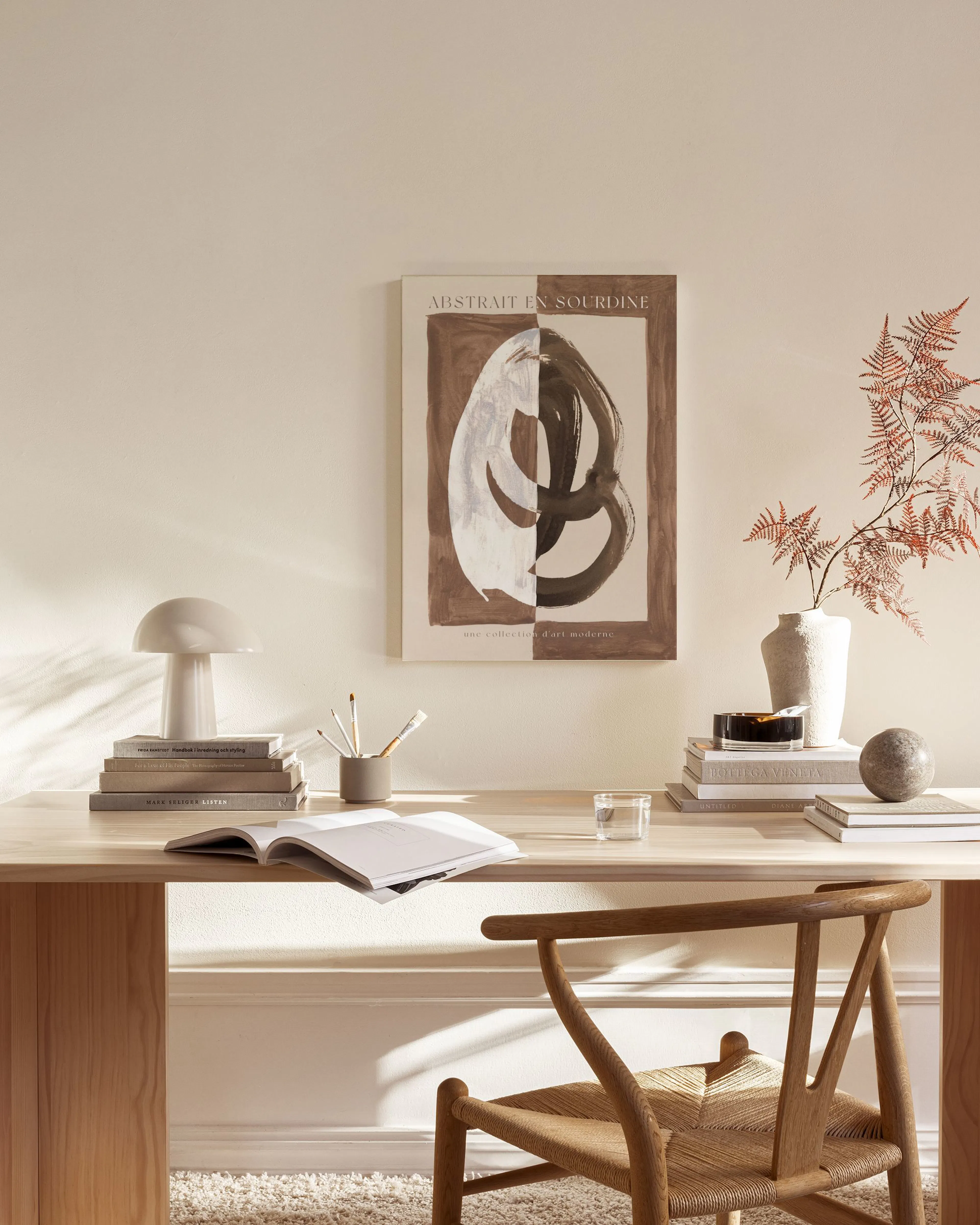 Abstract canvas print with white and dark brown organic shapes, reminiscent of a face, hanging in a minimalist living room.