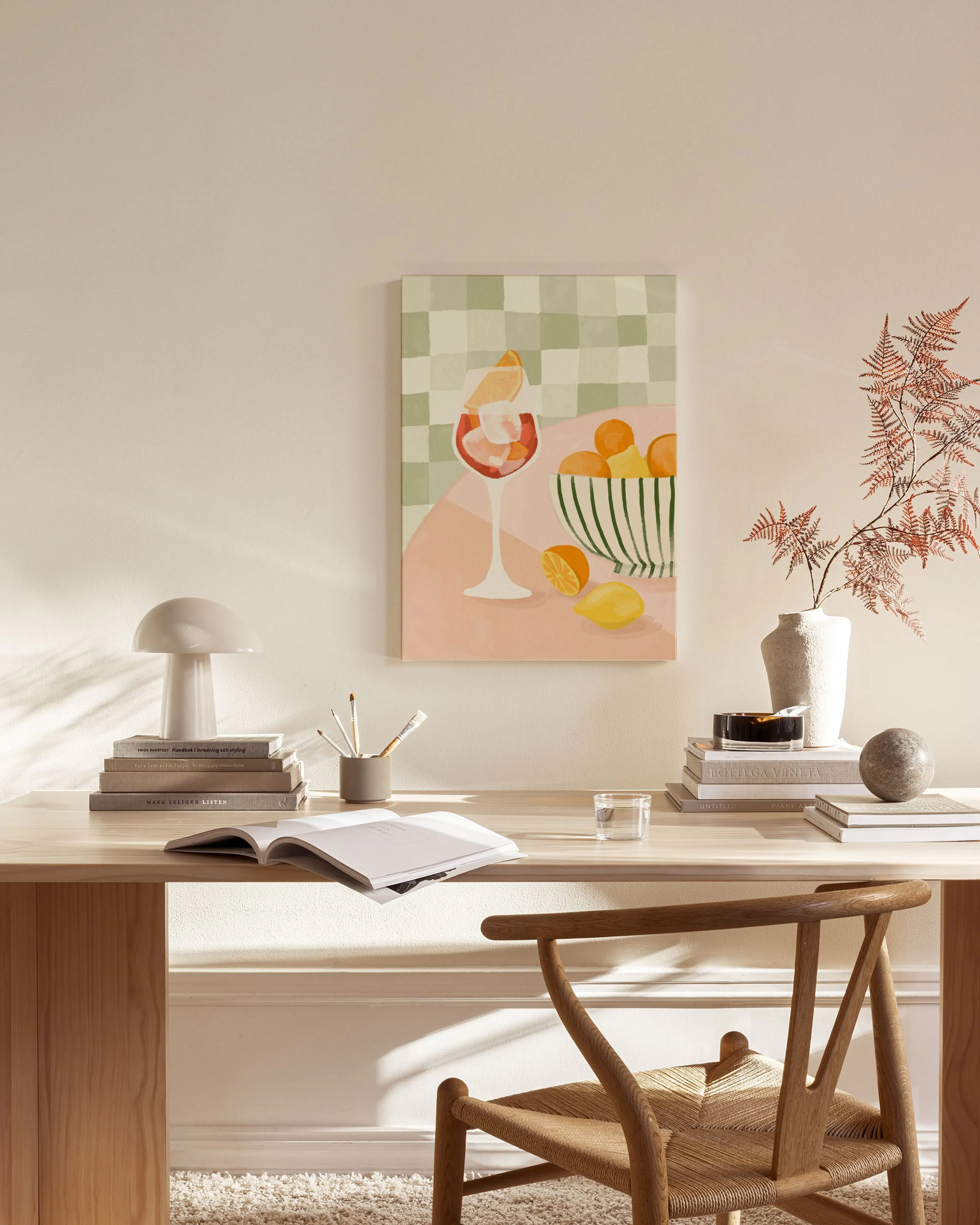 Toile aux couleurs pastel représentant un cocktail dagrumes et un bol de fruits, exposée dans un salon moderne.
