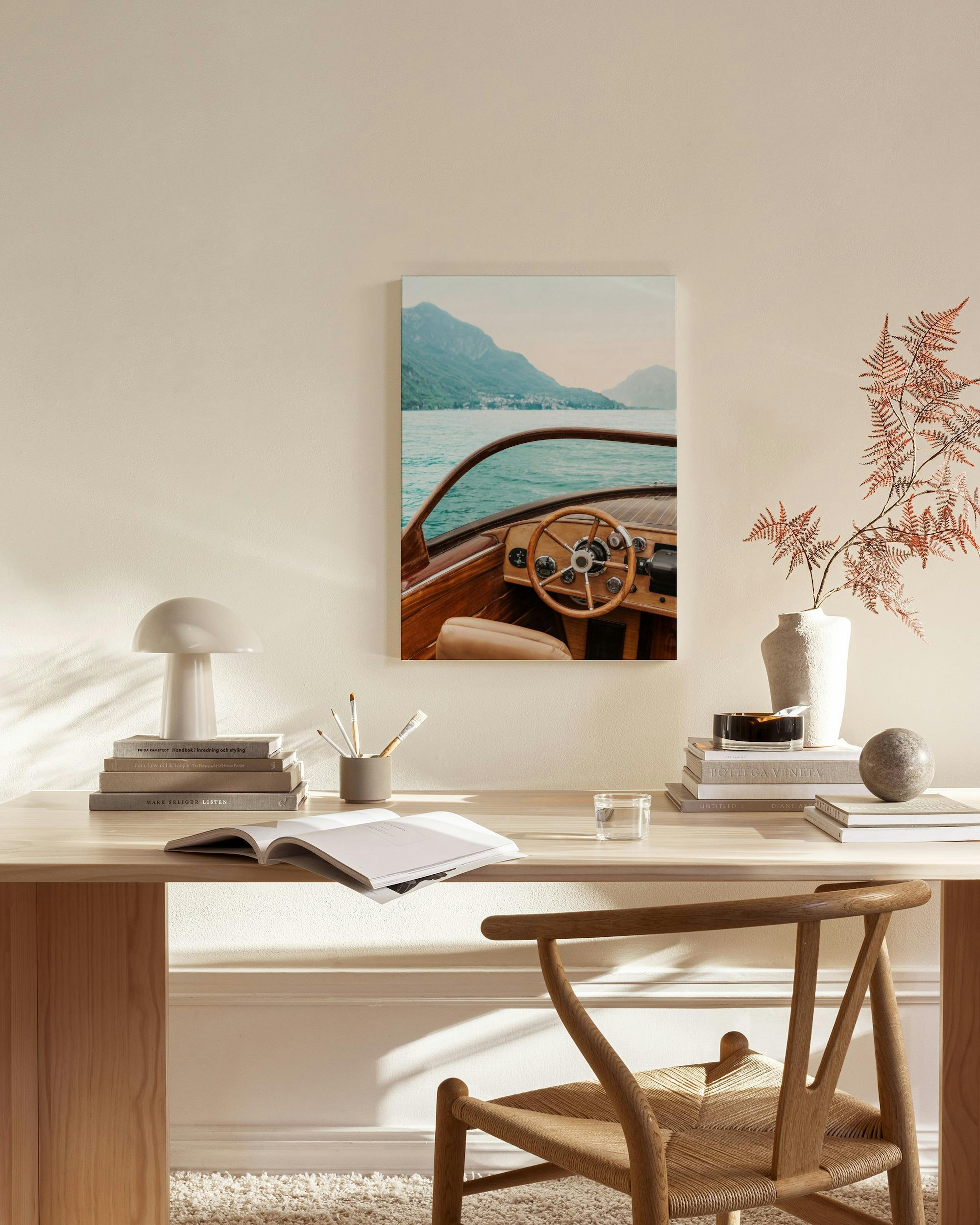 Een canvas van een houten boot op turquoise water met bergen op de achtergrond, hangend in een moderne woonkamer.